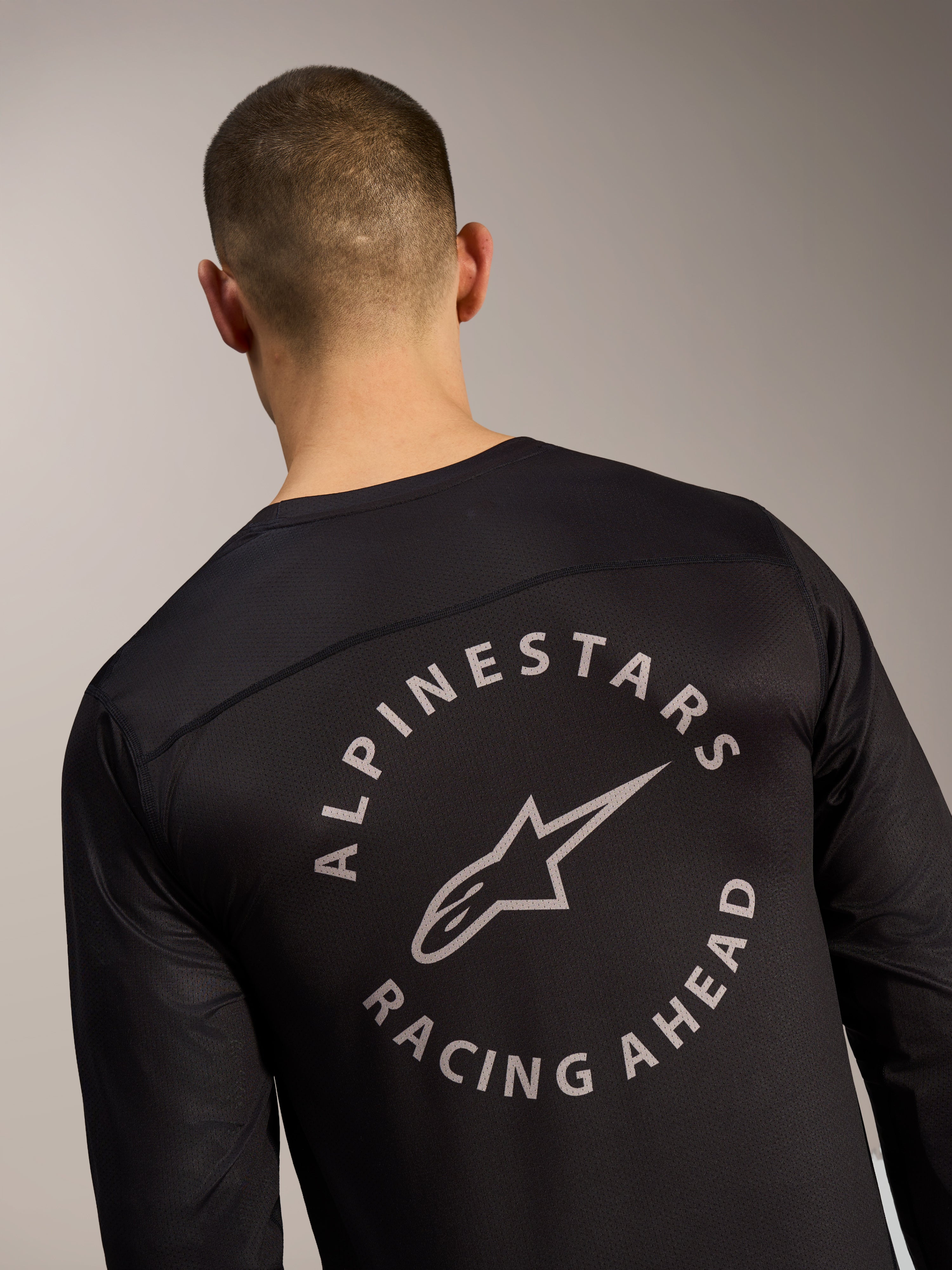 Czarna koszulka A-Dura Air z długim rękawem, detal pleców z okrągłym logo Alpinestars Racing Ahead na siatce.
