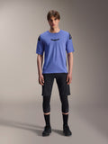 Alpinestars A-Aria Elite Shorts, MTB Mountain Biking Shorts, Black Titanium, worn with blue short-sleeve jersey, knee guards, and black biking shoes, full-body studio shot, performance mountain bike apparel