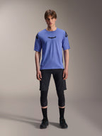 Alpinestars A-Aria Elite Shorts, MTB Mountain Biking Shorts, Black Titanium, worn with blue short-sleeve jersey, knee guards, and black biking shoes, full-body studio shot, performance mountain bike apparel