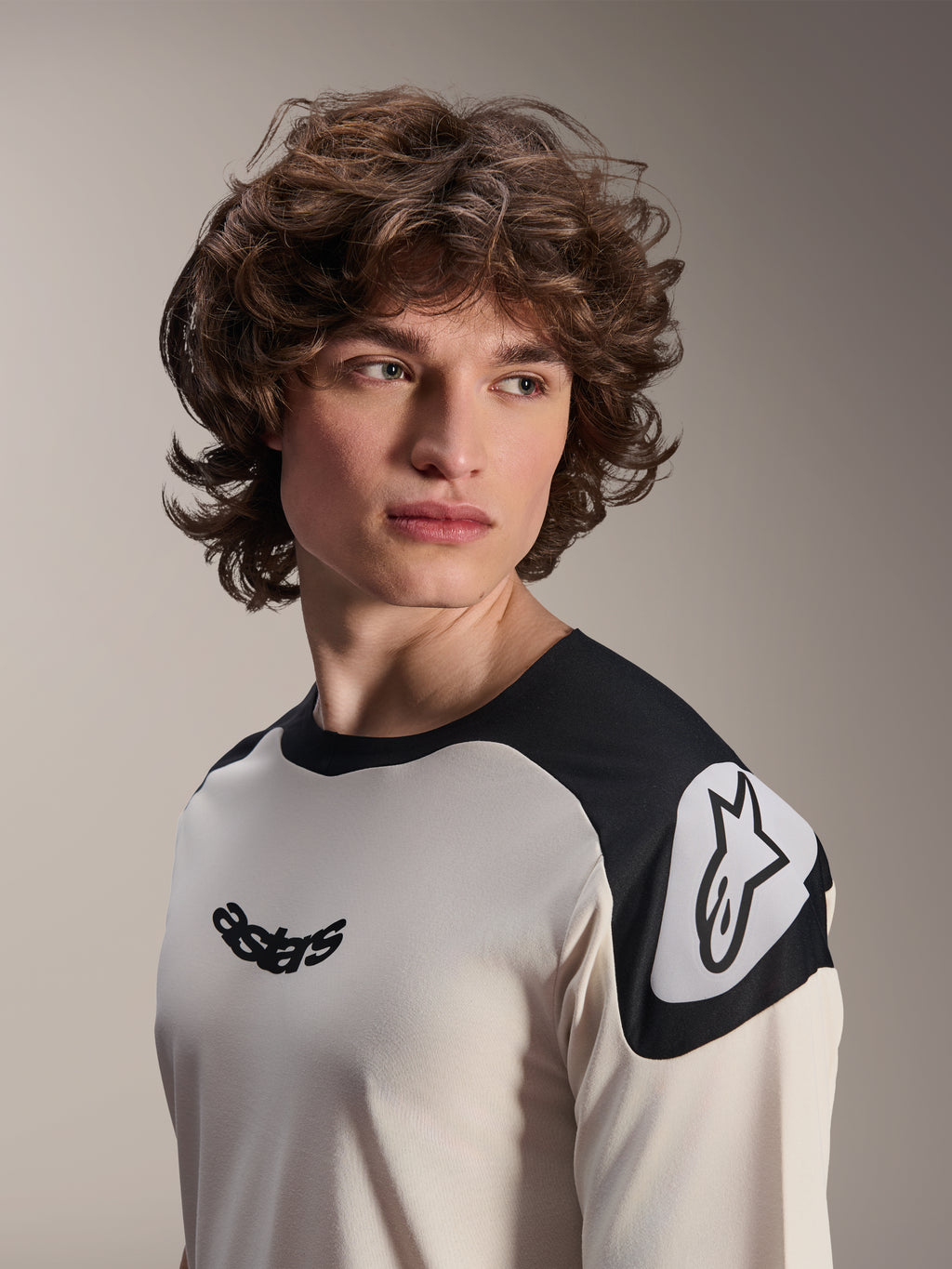 Alpinestars A-Aria Polartec Elite Short Sleeve Jersey, koszulka na rower górski, ecru z czarnymi panelami na ramionach, czarne logo astars na klatce piersiowej i białe logo Astars na ramieniu, wysokiej jakości odzież MTB noszona przez modela