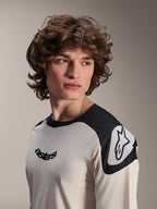 Alpinestars A-Aria Polartec Elite Short Sleeve Jersey, koszulka na rower górski, ecru z czarnymi panelami na ramionach, czarne logo astars na klatce piersiowej i białe logo Astars na ramieniu, wysokiej jakości odzież MTB noszona przez modela