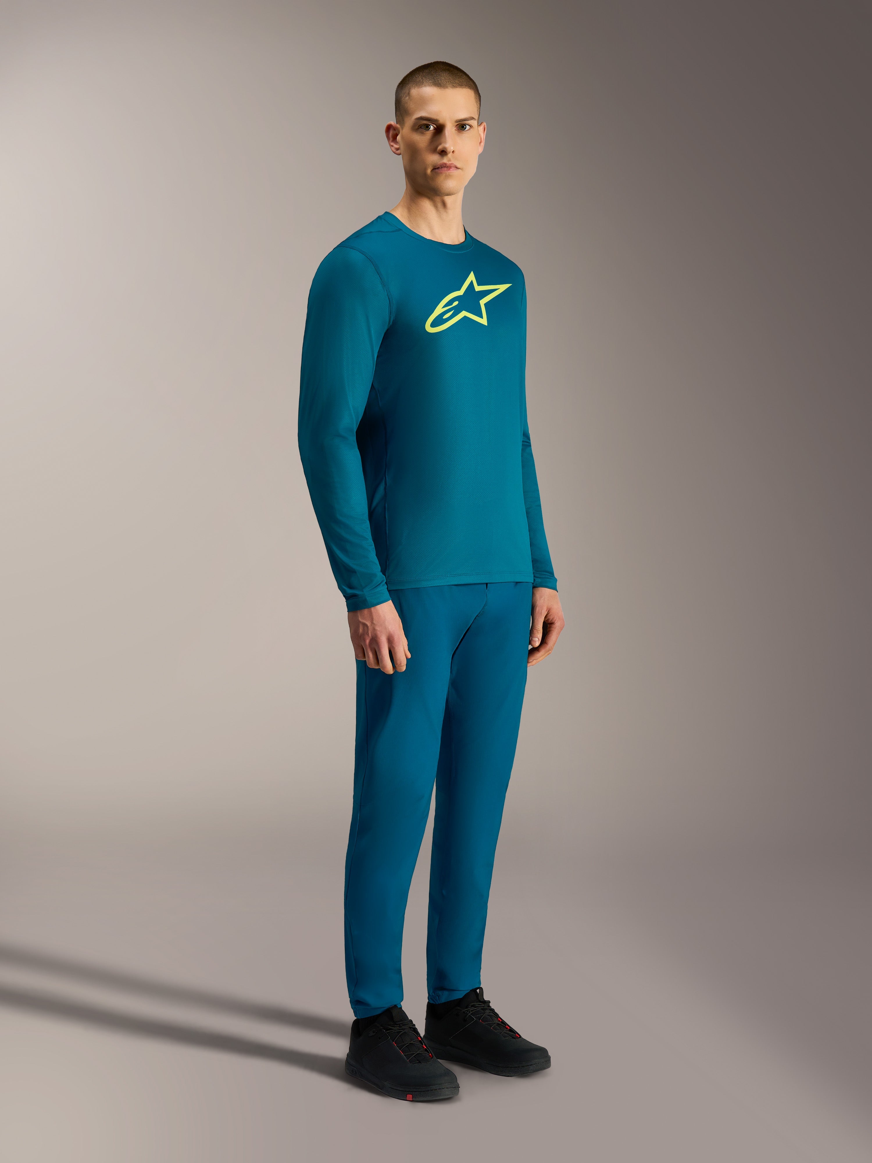 Niebiesko-zielona koszulka Alpinestars A-Dura Ride LS z żółtym logo Astars i spodniami MTB.