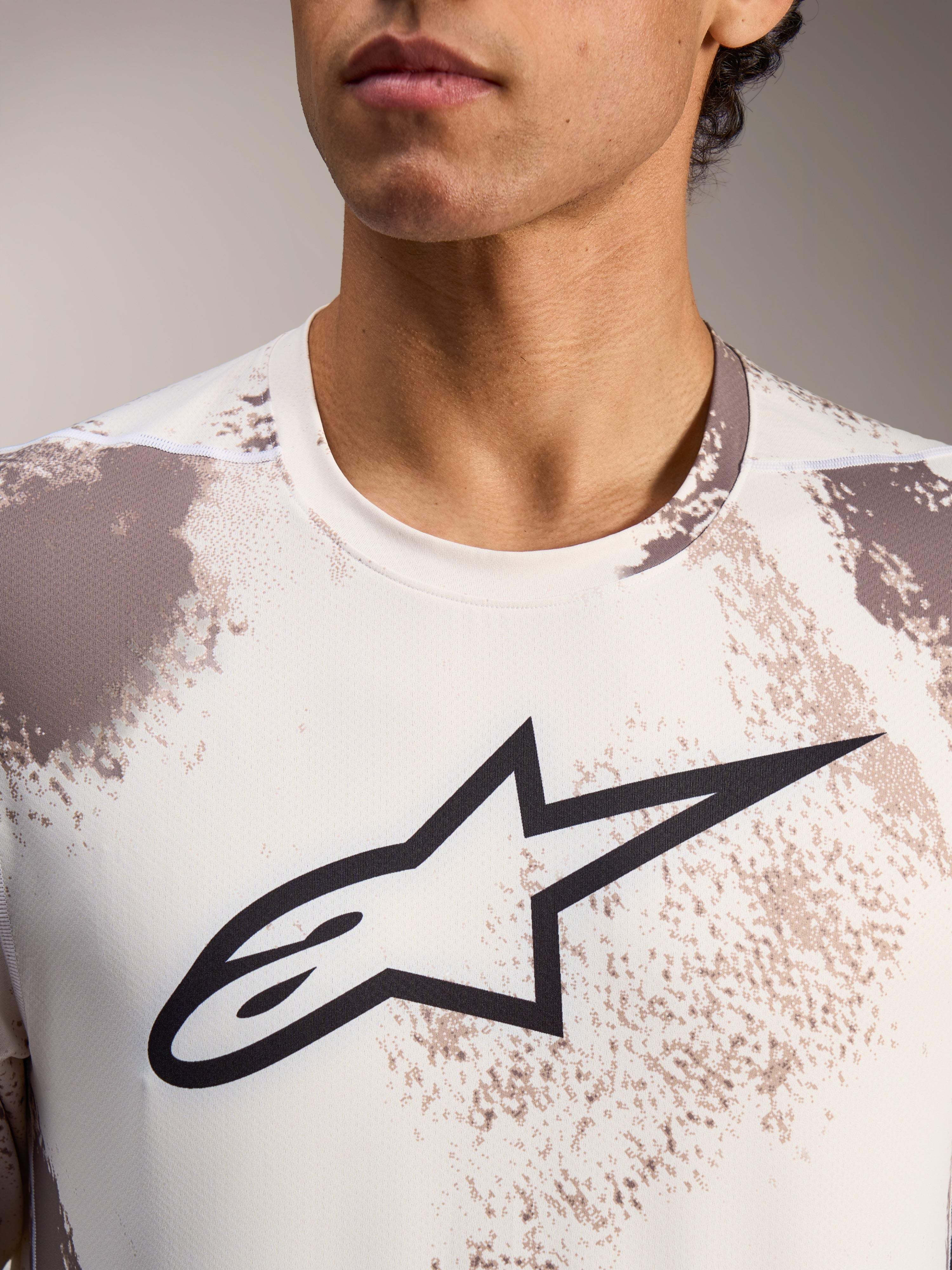 Koszulka A-Dura Ride z długim rękawem w kolorze Sand Camo, z czarnym logo Alpinestars i okrągłym dekoltem.