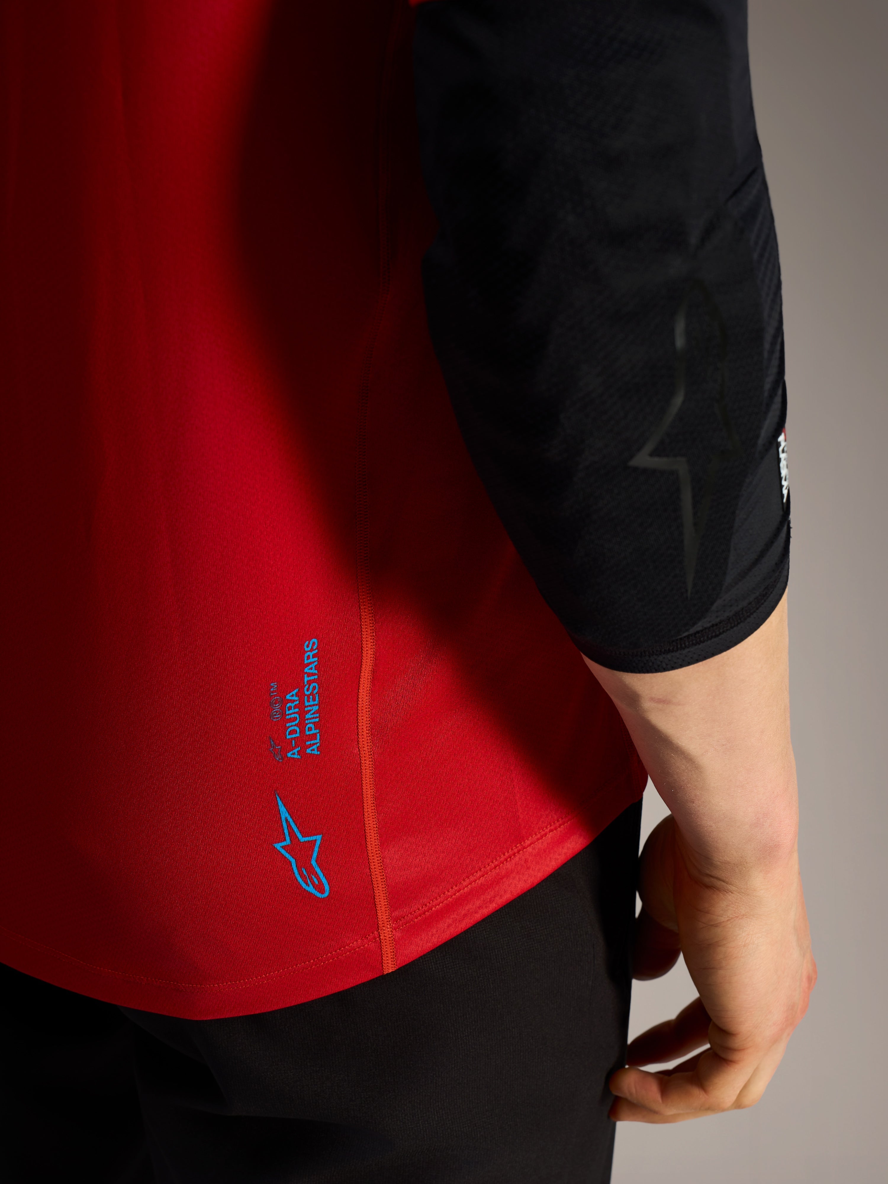 Czerwona koszulka A-Dura Ride MTB, niebieskie logo Alpinestars i techniczny materiał o wysokiej wydajności.
