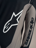 Szara koszulka A-Dura Race z długim rękawem, białe logo Astars na piersi i napis Alpinestars na rękawie.