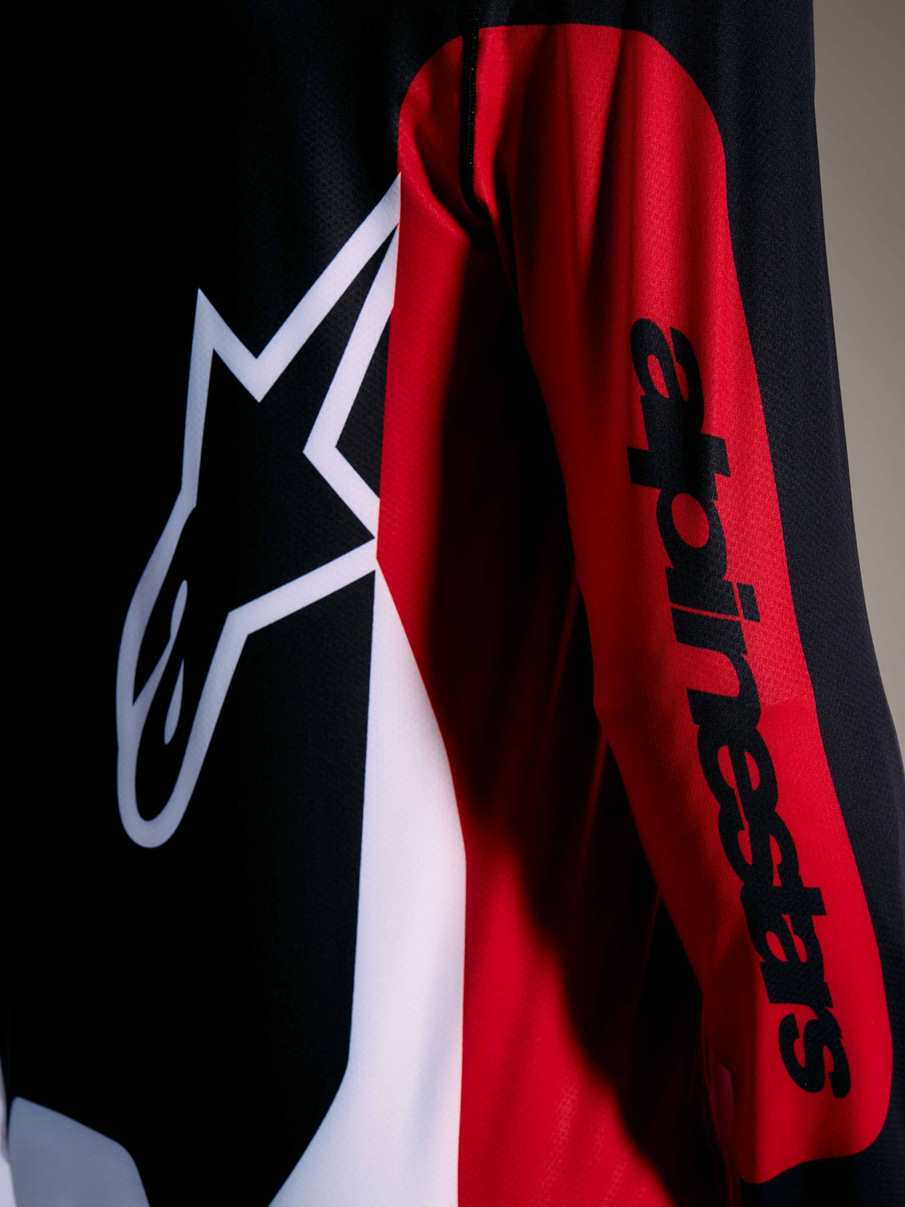 Czerwona koszulka A-Dura Race z białym logo Astars i czarnym napisem na rękawie, techniczna odzież MTB.