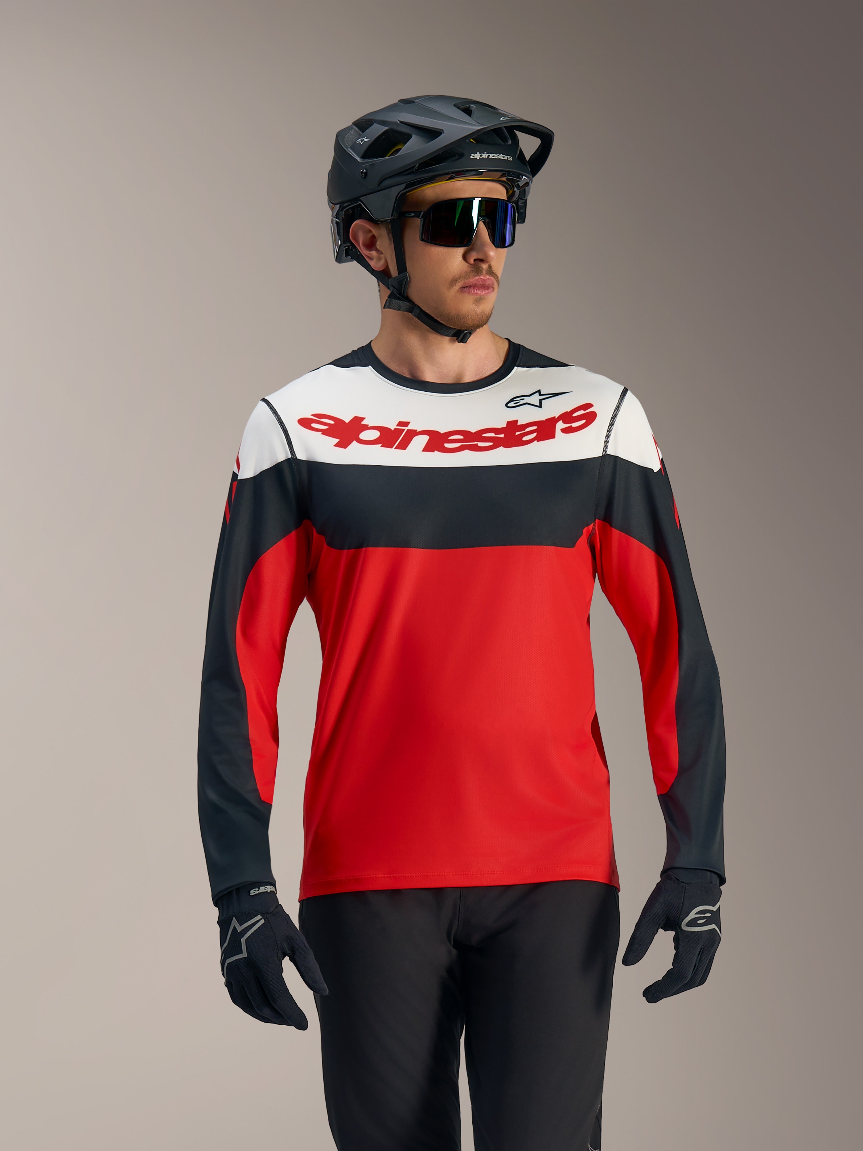 Koszulka A-Dura Race LS, czerwono-czarno-biała z logo Alpinestars, wyczynowy strój MTB z kaskiem i rękawicami.