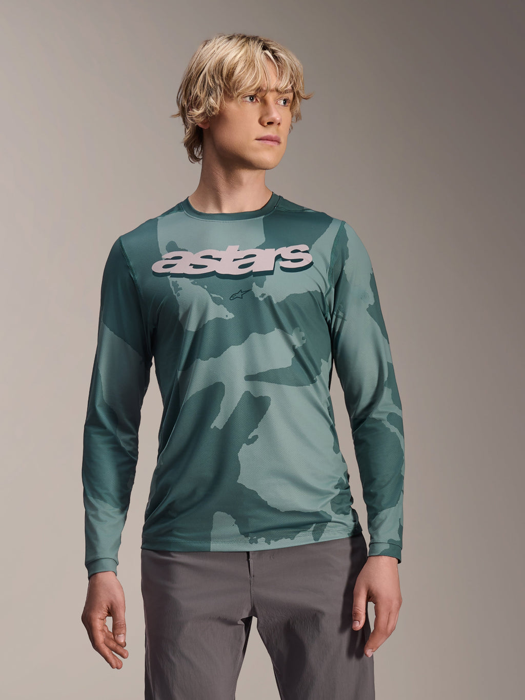 Alpinestars A-Dura Hollow Camo Long Sleeve Jersey, koszulka MTB z długim rękawem, zielony wzór moro Silver Pine Camo, duże jasnoszare logo astars na piersi, zestawiona z szarymi spodniami, profesjonalna odzież do kolarstwa górskiego