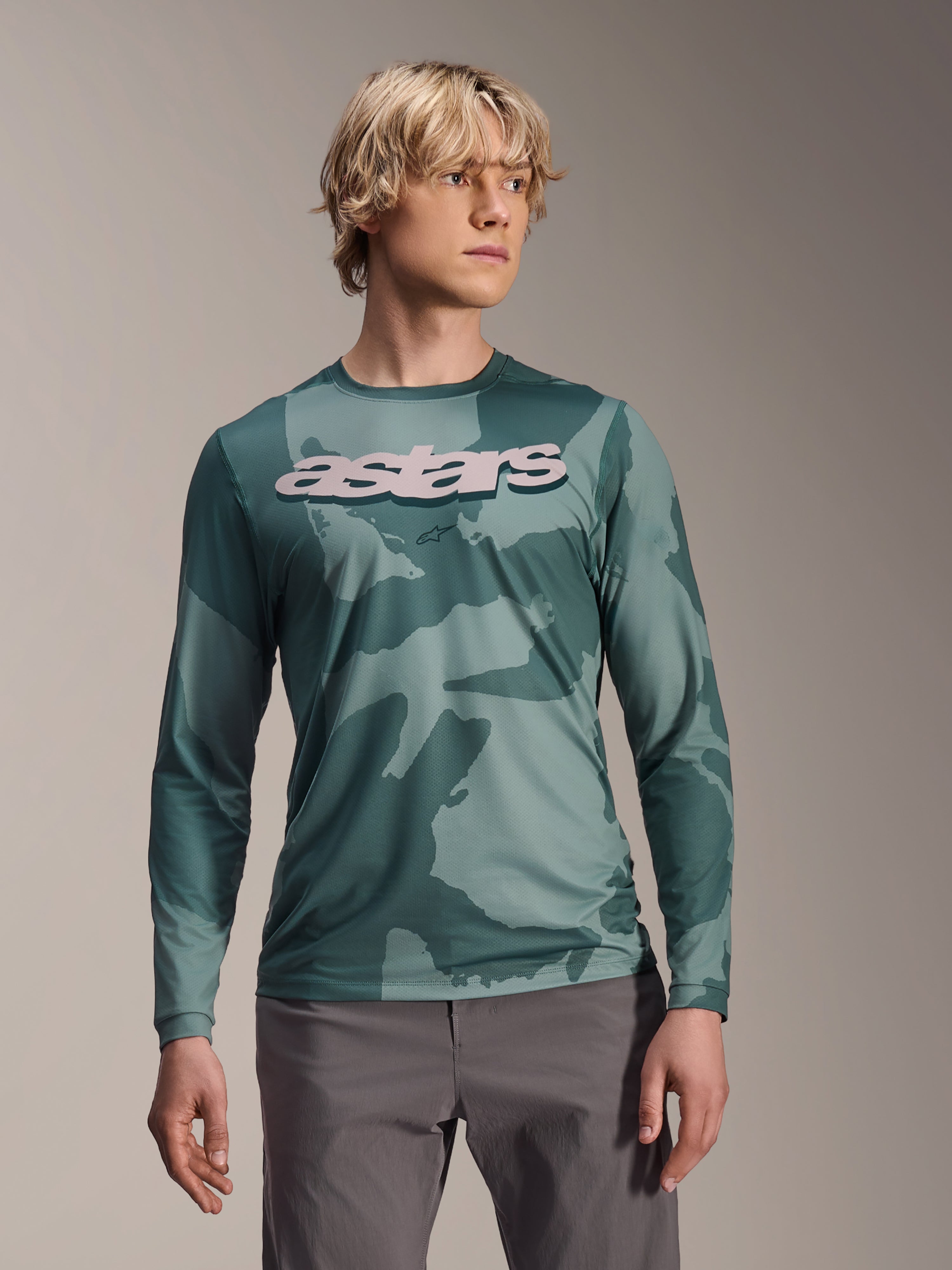 Alpinestars A-Dura Hollow Camo Long Sleeve Jersey, koszulka MTB z długim rękawem, zielony wzór moro Silver Pine Camo, duże jasnoszare logo astars na piersi, zestawiona z szarymi spodniami, profesjonalna odzież do kolarstwa górskiego
