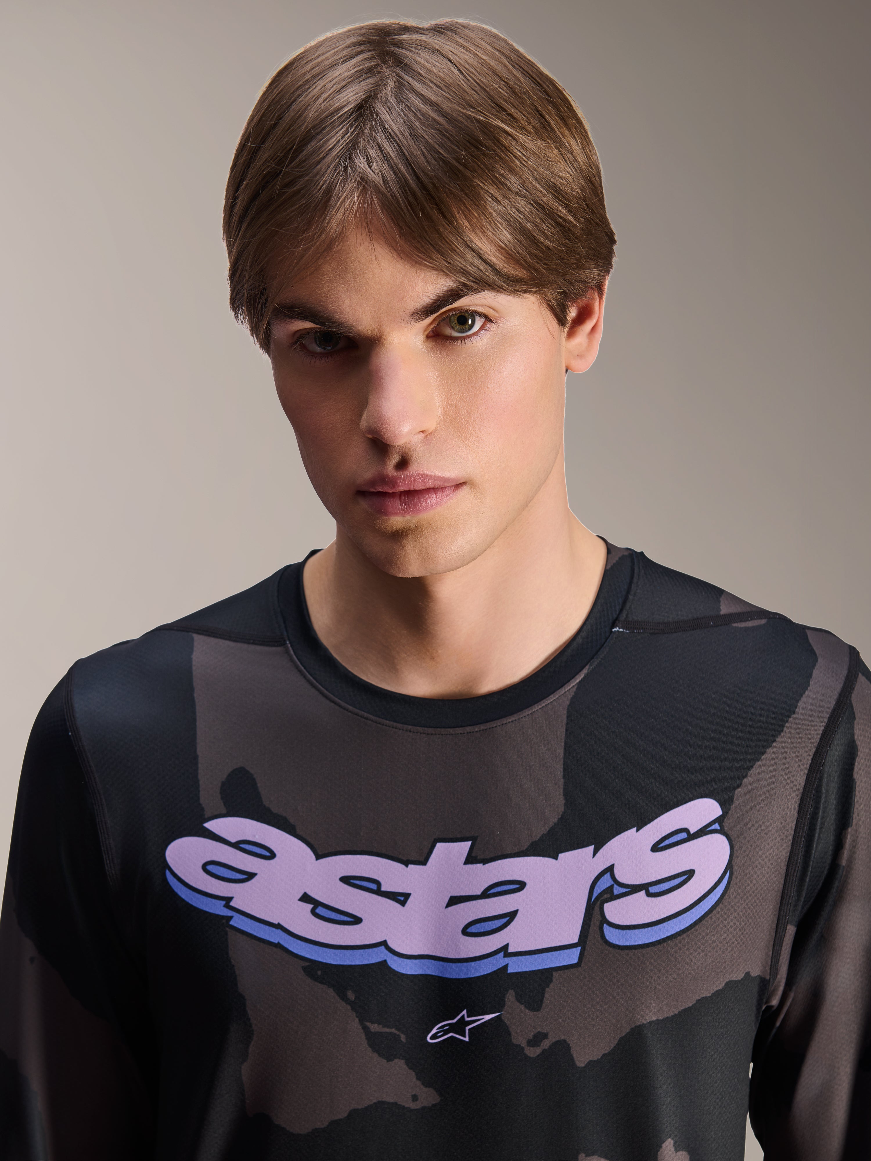 Alpinestars A-Dura Hollow Camo Jersey - Long Sleeve, koszulka z długim rękawem, czarny kamuflaż z fioletową grafiką „astars” na klatce piersiowej, zdjęcie studyjne męskiego modela, casualowy i techniczny styl MTB