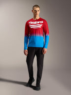 Koszulka MTB A-Dura ASTARS 2.0, czerwono-niebieski gradient, białe logo, długi rękaw, model w czarnych spodniach.