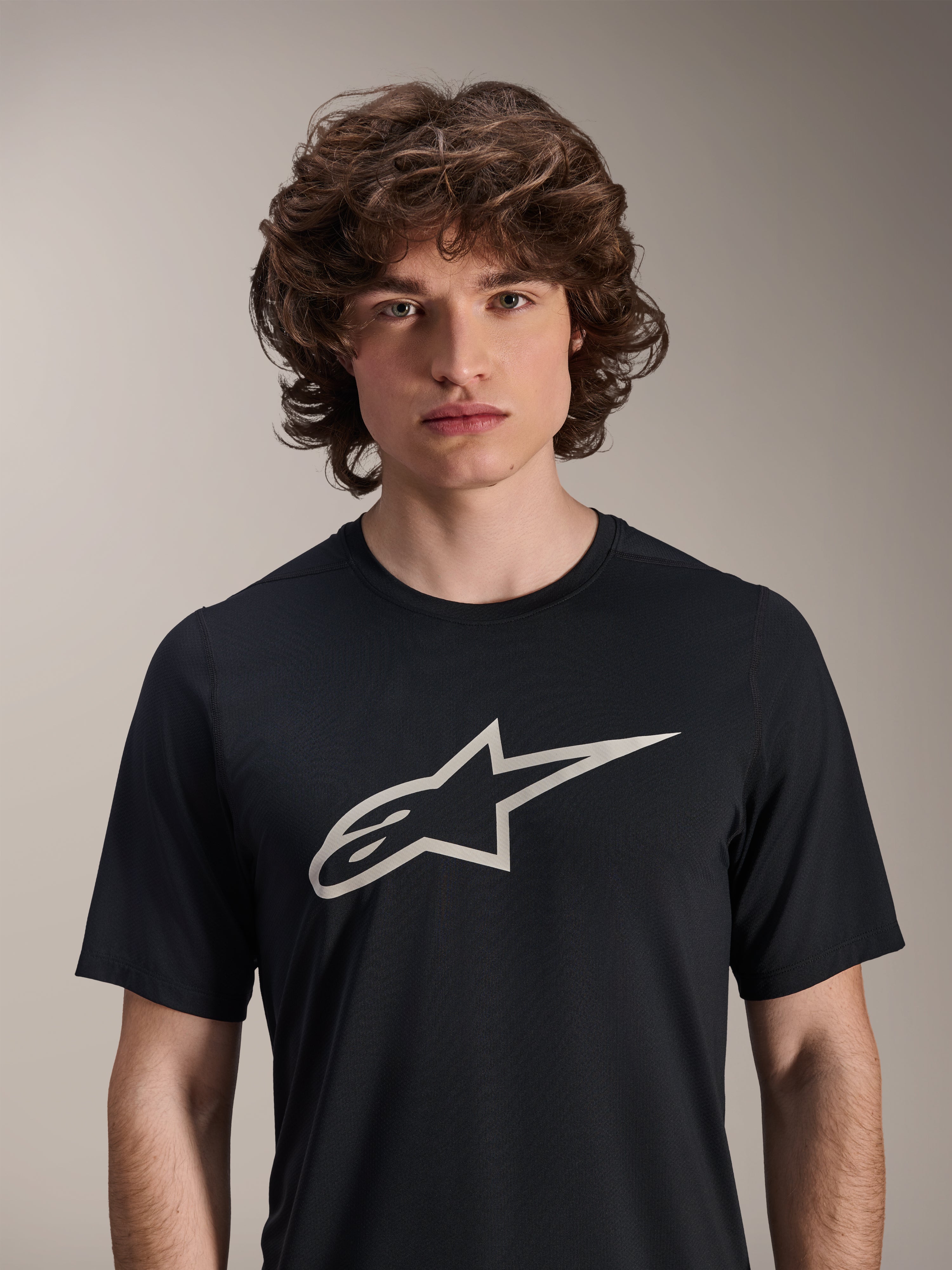 Alpinestars A-Dura Astar Short Sleeve Jersey, czarna koszulka z krótkim rękawem, z dużym białym logo Astar na piersi, prezentowana na modelu, codzienna techniczna odzież rowerowa MTB