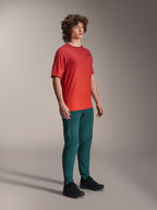 Model ubrany w spodnie Alpinestars A-Dura w kolorze Dark Pine, w połączeniu z czerwoną koszulką z krótkim rękawem A-Dura Rise i czarnymi butami MTB, sportowa odzież do kolarstwa górskiego w studio