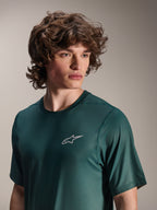 Alpinestars A-Dura Rise Jersey - krótki rękaw, kolor Silver Pine (ciemnozielony), noszona przez modela, małe białe logo Astars na piersi, techniczna dzianina żakardowa, swobodna odzież na rower górski