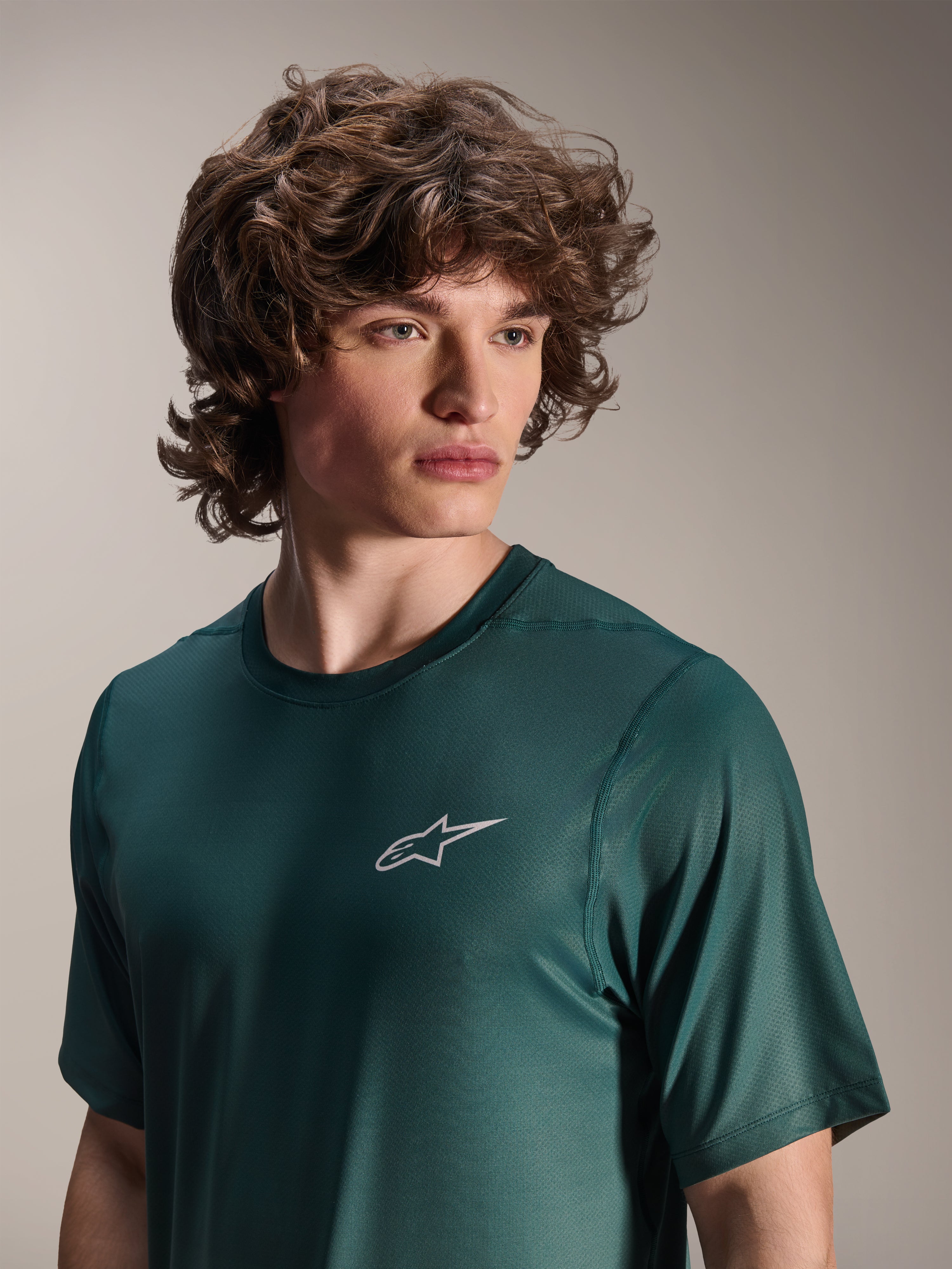 Alpinestars A-Dura Rise Jersey - krótki rękaw, kolor Silver Pine (ciemnozielony), noszona przez modela, małe białe logo Astars na piersi, techniczna dzianina żakardowa, swobodna odzież na rower górski
