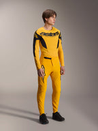 Model wearing Alpinestars Limited Edition A-Supra Melt Gold Jersey, long sleeve MTB jersey in Dark Yellow and Black, paired with matching yellow pants and black shoes, technical off-road cycling gear with racing-inspired graphics