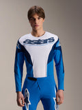 Alpinestars A-Supra Melt Jersey z długim rękawem, niebiesko-biała koszulka MTB, z wyraźnym brandingiem astars na klatce piersiowej, ciemnoniebieskie rękawy, noszona z pasującymi niebieskimi spodniami wyścigowymi z białym logo gwiazdy, profesjonalna odzież do kolarstwa górskiego