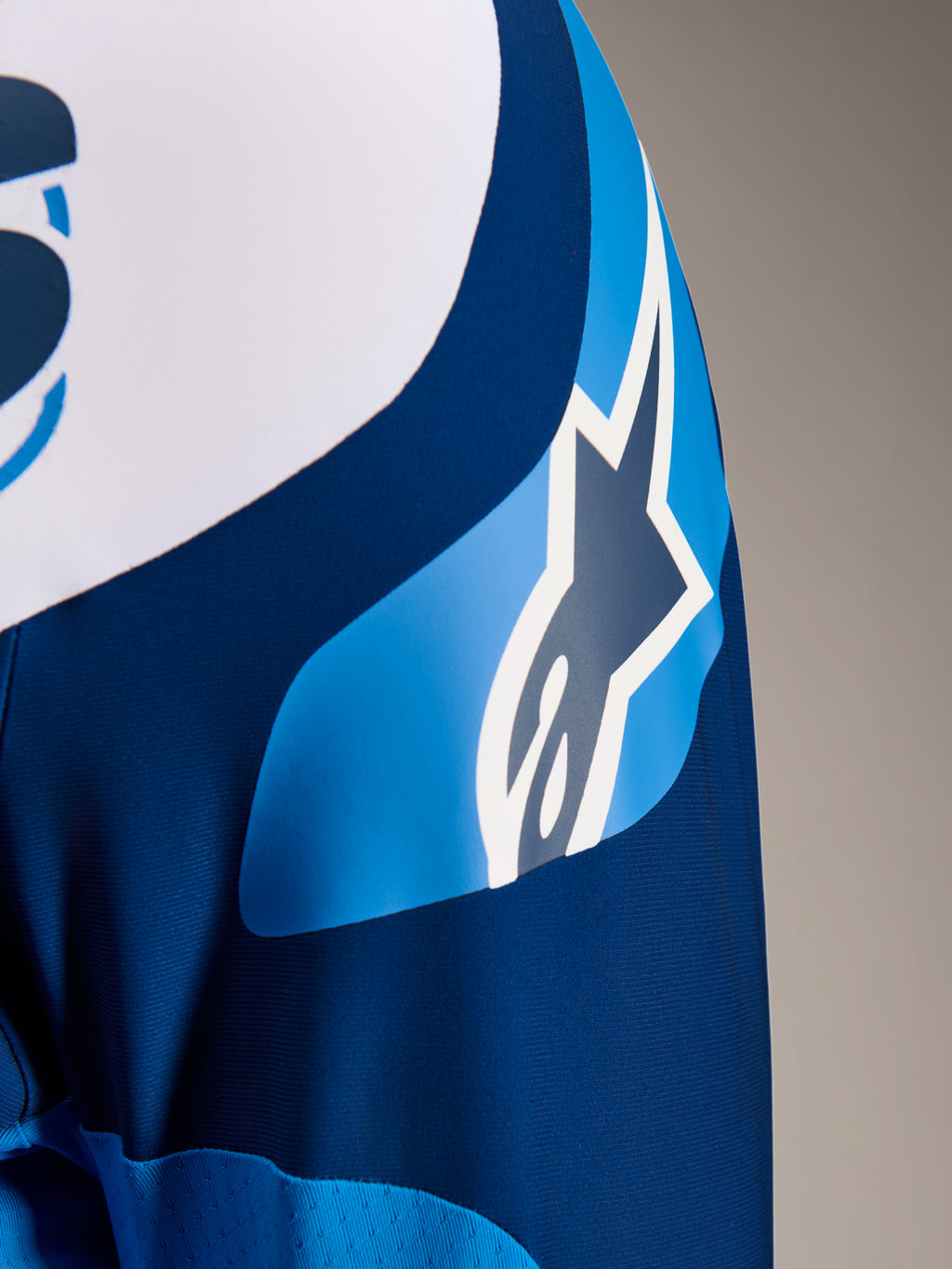Alpinestars A-Supra Melt Jersey, niebieska koszulka MTB z długim rękawem, zbliżenie na rękaw z grafiką logo ASTARS i mikroperforowaną tkaniną zapewniającą wentylację