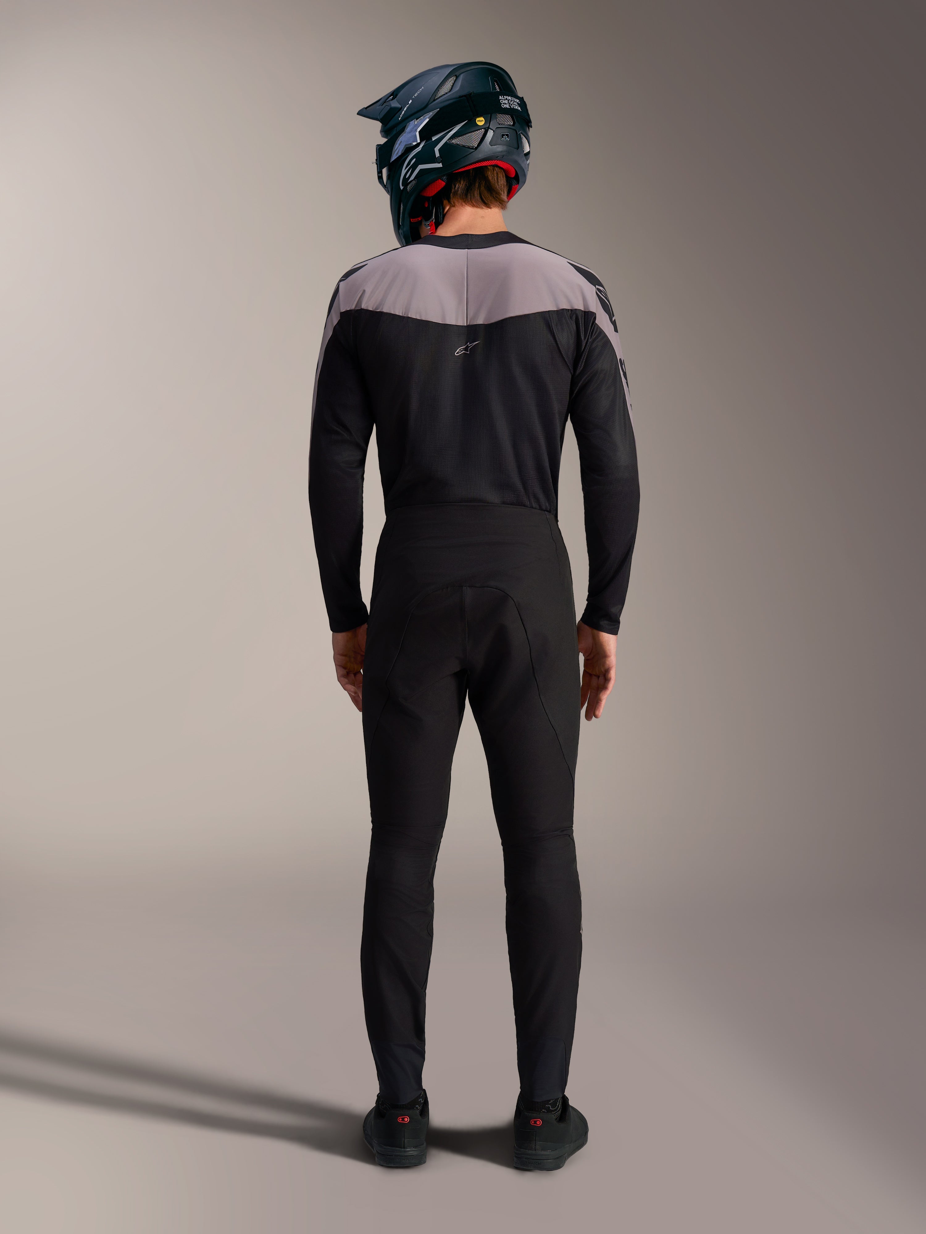 Czarny zestaw MTB Alpinestars A-Supra Elite, techniczne spodnie i bluza z kaskiem full-face, widok z tyłu.