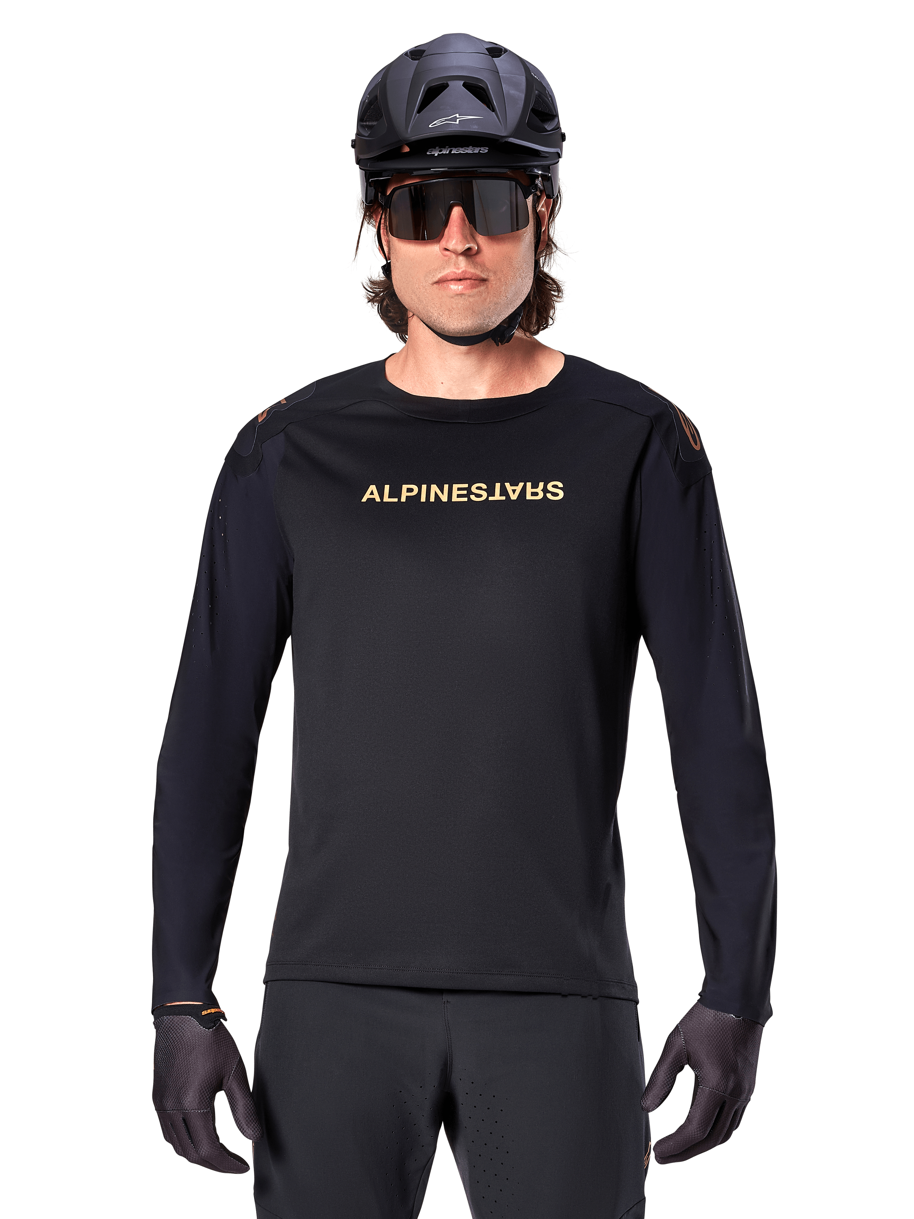 Alpinestars A-Aria Polartec Switch Long Sleeve Jersey, czarna, złote logo Alpinestars na piersi, noszona z czarnym kaskiem MTB, ciemnymi okularami i czarnymi rękawiczkami, profesjonalna odzież na rower górski