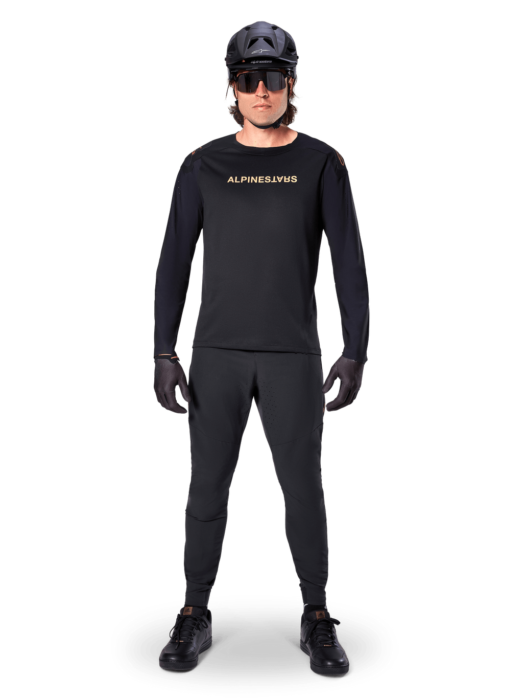 Alpinestars A-Aria Polartec Switch Long Sleeve Jersey, czarna, prezentowana przez kolarza w komplecie z czarnymi spodniami technicznymi, czarnym kaskiem, okularami przeciwsłonecznymi i czarnymi rękawicami, profesjonalny strój MTB na terenowe szlaki