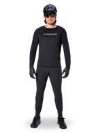 Alpinestars A-Aria Polartec Switch Long Sleeve Jersey, czarna, prezentowana przez kolarza w komplecie z czarnymi spodniami technicznymi, czarnym kaskiem, okularami przeciwsłonecznymi i czarnymi rękawicami, profesjonalny strój MTB na terenowe szlaki