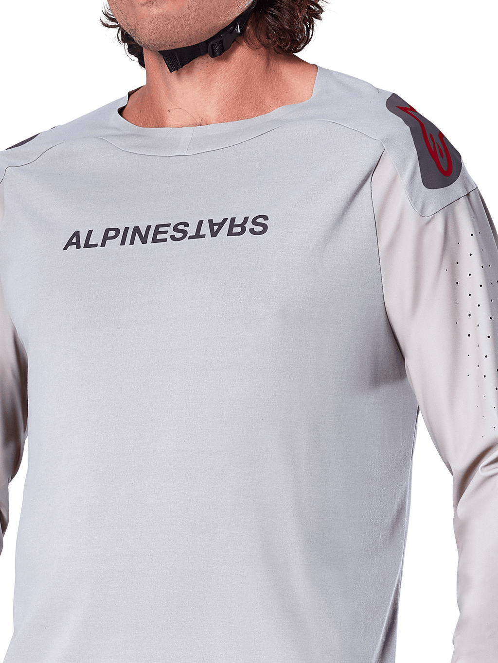 Zbliżenie na jasnoszarą koszulkę z długim rękawem Alpinestars A-Aria Polartec Switch, logo Alpinestars na piersi, czerwone logo na ramieniu i laserowo perforowane rękawy zapewniające przepływ powietrza, wysokiej jakości odzież MTB