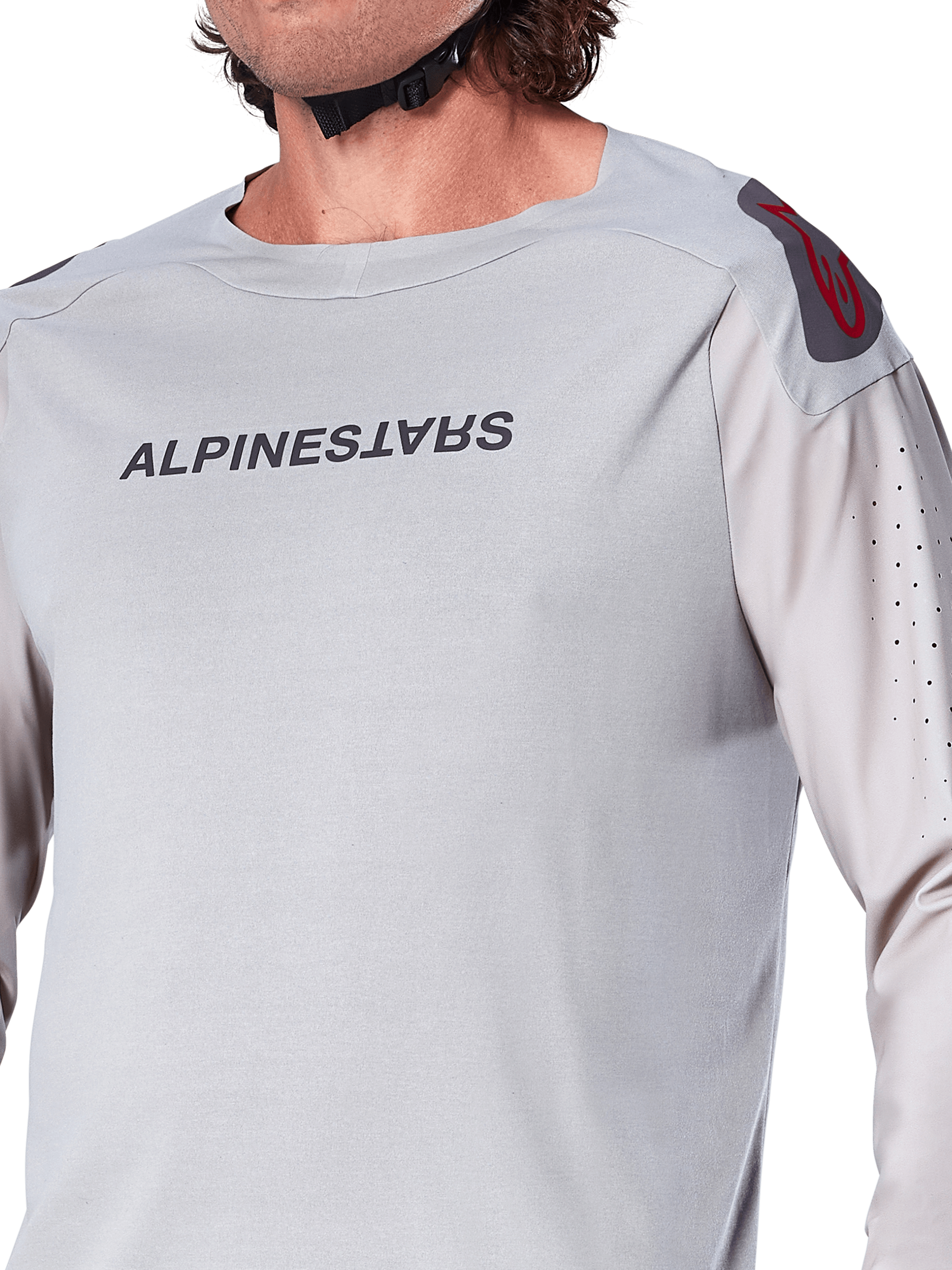 Zbliżenie na jasnoszarą koszulkę z długim rękawem Alpinestars A-Aria Polartec Switch, logo Alpinestars na piersi, czerwone logo na ramieniu i laserowo perforowane rękawy zapewniające przepływ powietrza, wysokiej jakości odzież MTB