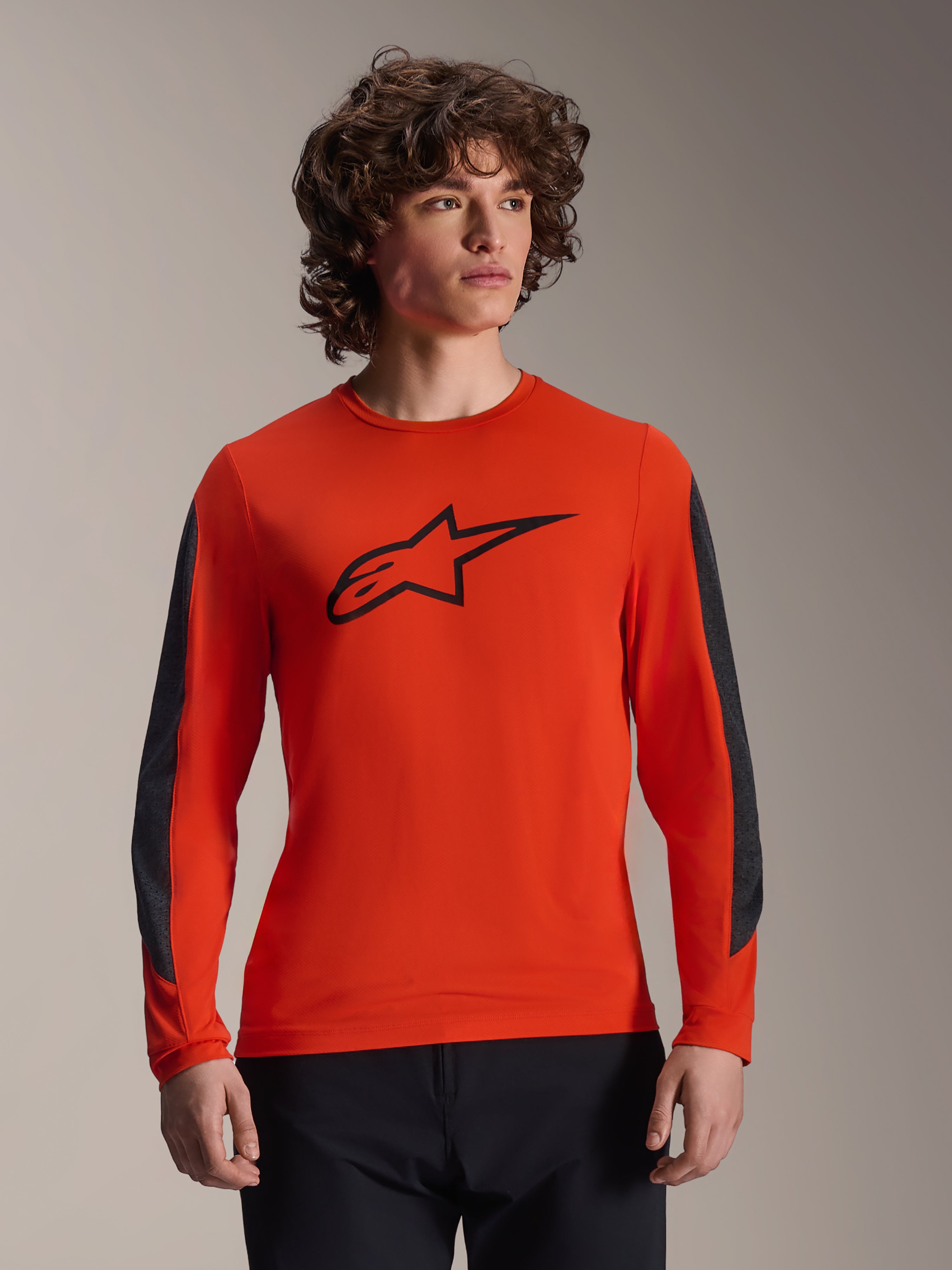 Alpinestars A-Dura Insert Astar Jersey, koszulka z długim rękawem, kolor Spicy Orange z czarnym logo Astar, ciemnoszare wytrzymałe wstawki na rękawach, prezentowana przez modela, profesjonalna odzież rowerowa MTB