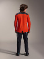 Koszulka z długim rękawem Alpinestars A-Dura Insert Astar w kolorze Spicy Orange, widok z tyłu prezentujący grafitowy panel na ramionach, noszona z czarnymi spodniami Alpinestars i czarnymi butami, profesjonalne zdjęcie studyjne odzieży MTB