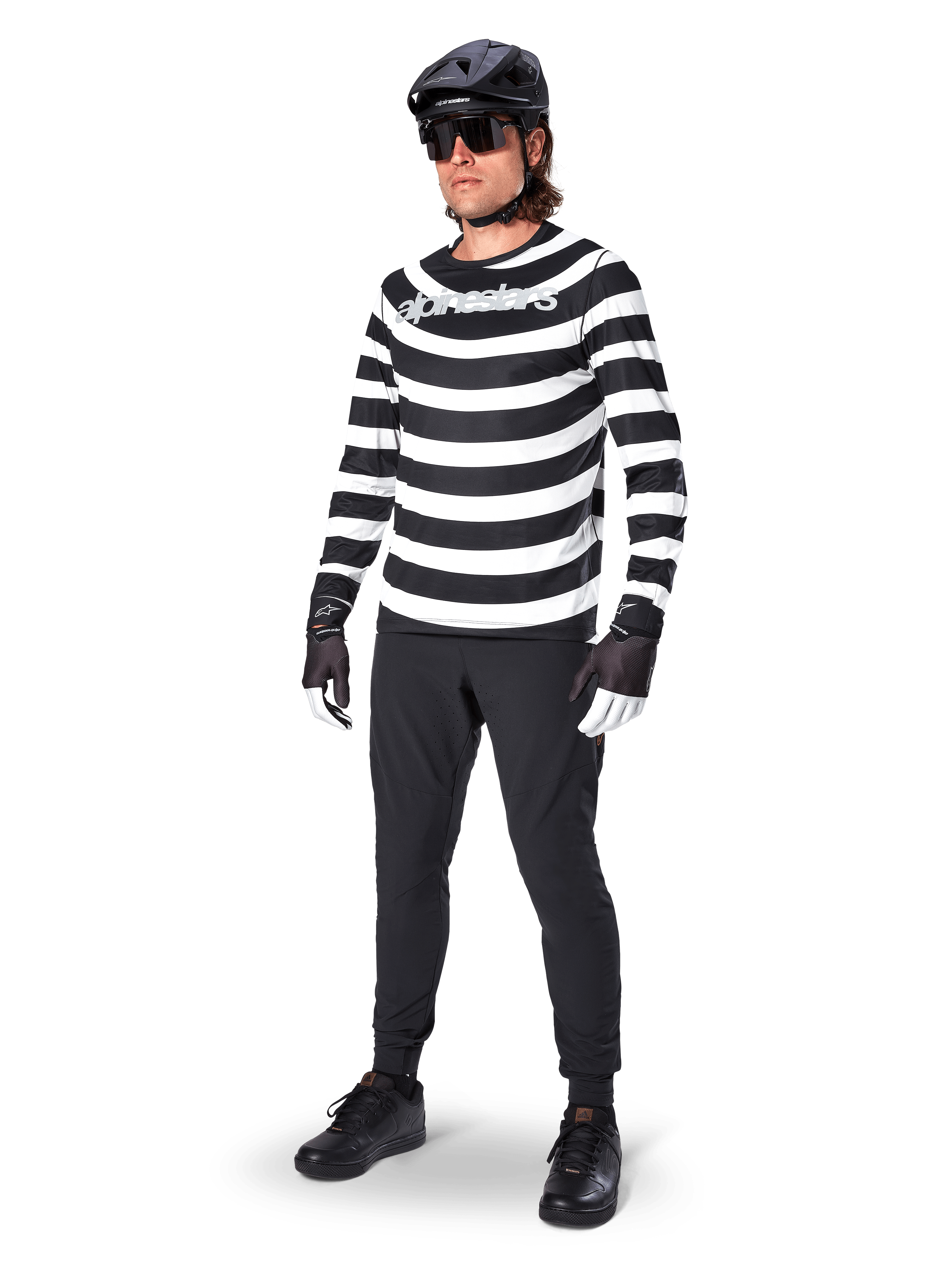 Alpinestars A-Aria Oscar Long Sleeve Jersey, czarno-biała koszulka z długim rękawem w wyraźne poziome, spiralne pasy, białe zakrzywione logo Alpinestars, sportowa odzież MTB noszona z czarnymi spodniami rowerowymi i kaskiem
