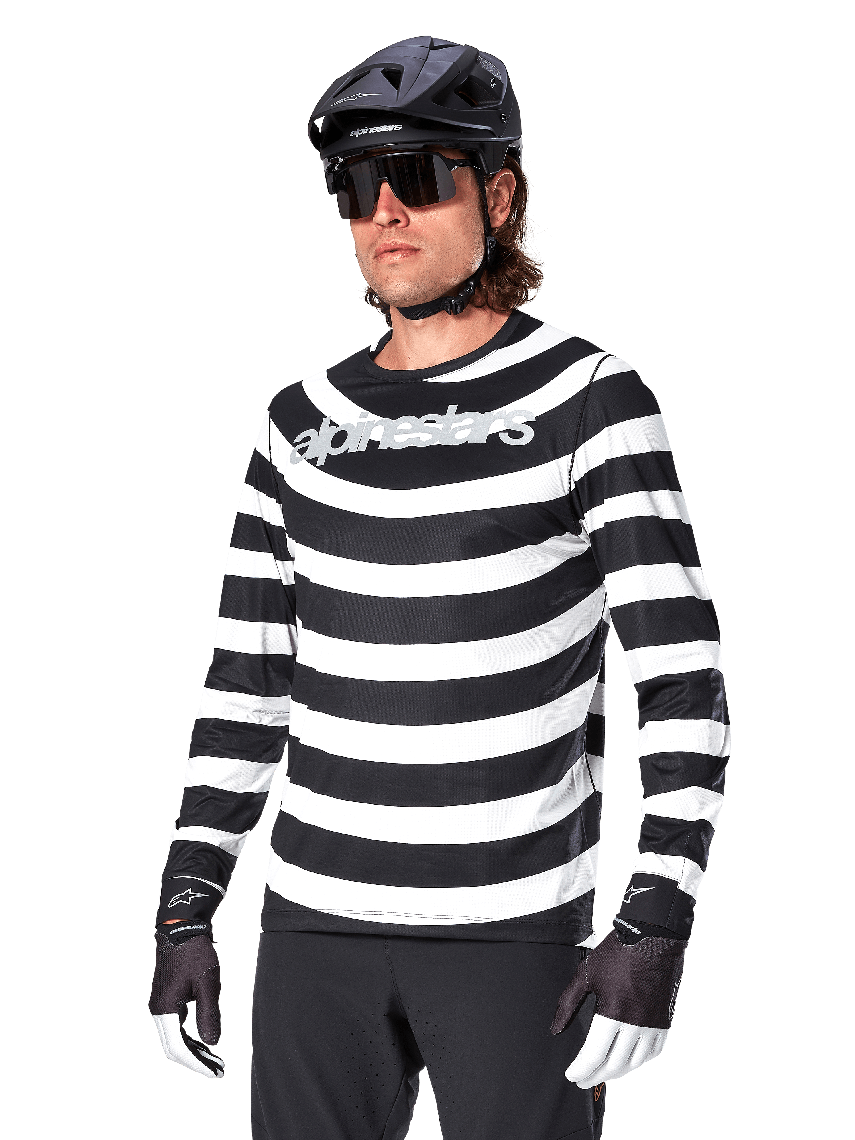 Koszulka z długim rękawem Alpinestars A-Aria Oscar, koszulka rowerowa MTB, czarno-białe poziome pasy, noszona z czarnym kaskiem i okularami przeciwsłonecznymi, z logo Alpinestars na piersi, profesjonalna odzież do kolarstwa górskiego