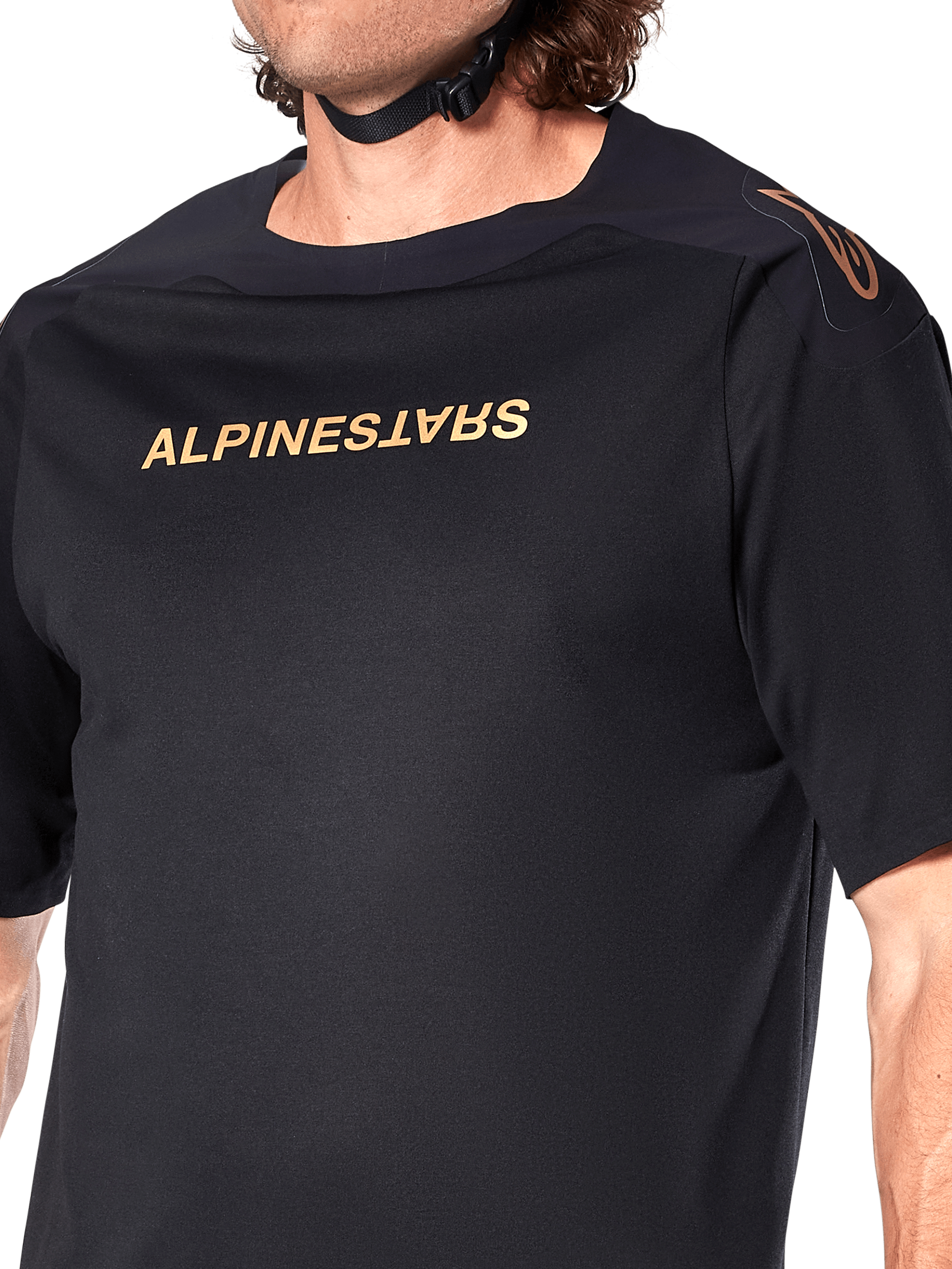 Alpinestars A-Aria Polartec Switch Jersey, koszulka MTB z krótkim rękawem, czarna, złoty napis Alpinestars na klatce piersiowej i logo na ramieniu, zbliżenie na górną część tułowia podkreślające techniczny materiał i sportowy krój
