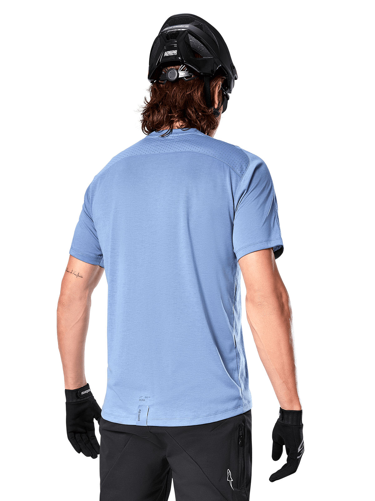 Koszulka Alpinestars A-Dura Dri Astar z krótkim rękawem, koszulka MTB, niebieska (Infinity Blue), widok z tyłu ukazujący siatkowe panele wentylacyjne na ramionach i przedłużony tył, noszona z czarnym kaskiem MTB i rękawiczkami, profesjonalna odzież rowerowa
