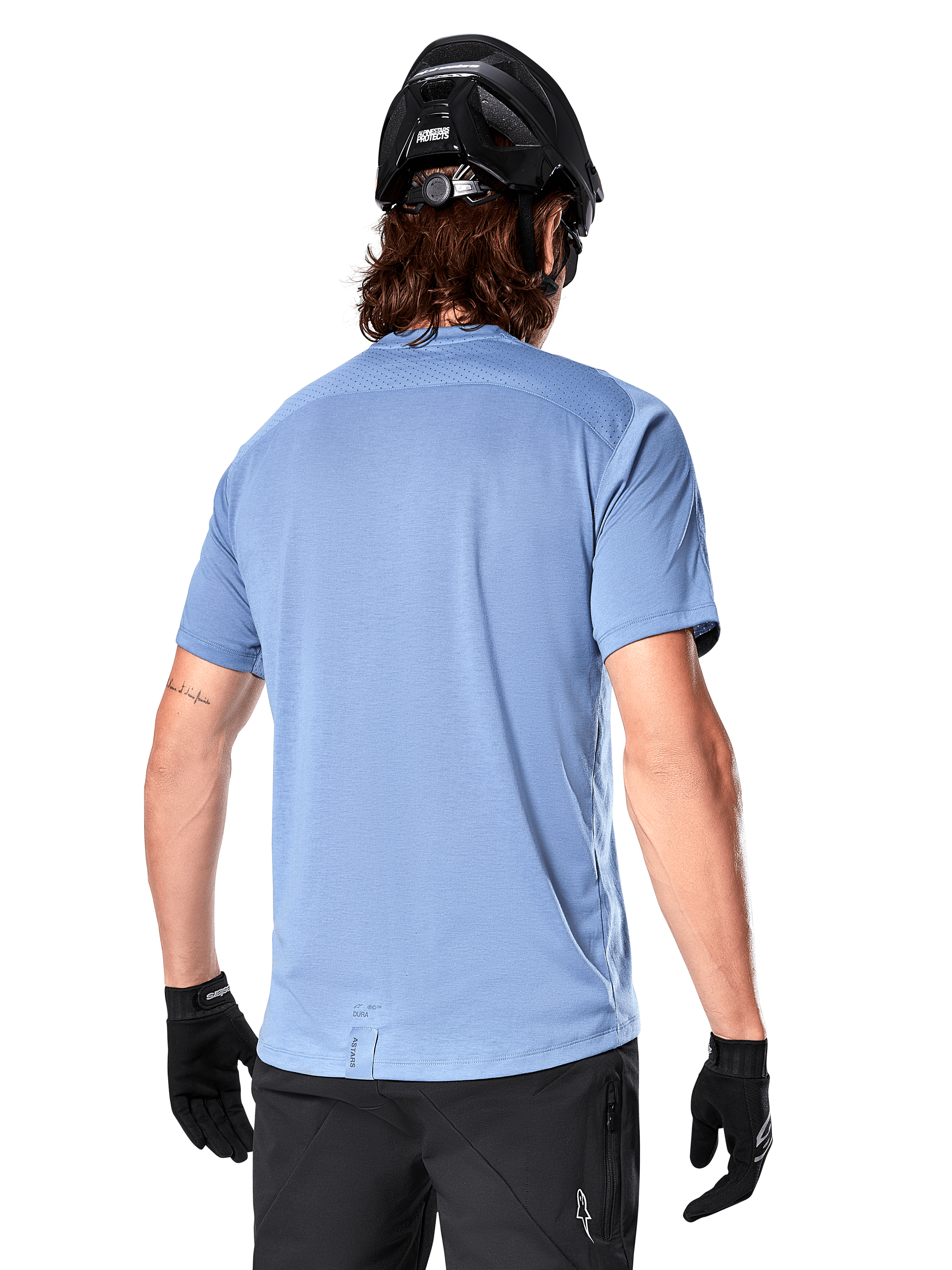 Koszulka Alpinestars A-Dura Dri Astar z krótkim rękawem, koszulka MTB, niebieska (Infinity Blue), widok z tyłu ukazujący siatkowe panele wentylacyjne na ramionach i przedłużony tył, noszona z czarnym kaskiem MTB i rękawiczkami, profesjonalna odzież rowerowa