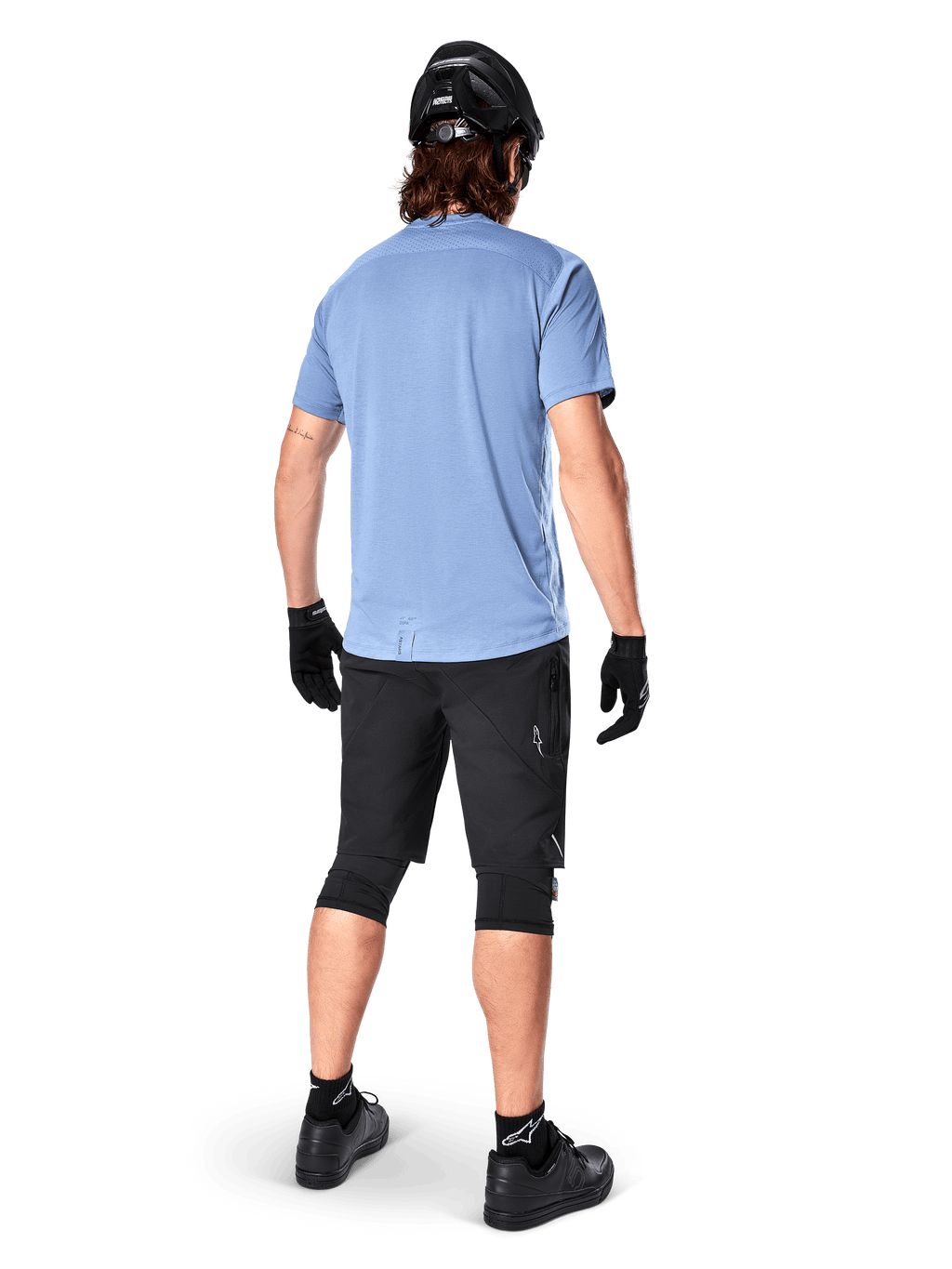 Koszulka z krótkim rękawem Alpinestars A-Dura Dri Astar, kolor Infinity Blue, widok z tyłu, zestawiona z czarnymi szortami rowerowymi i kaskiem, techniczna odzież rowerowa z materiału odprowadzającego wilgoć, przedłużony tył