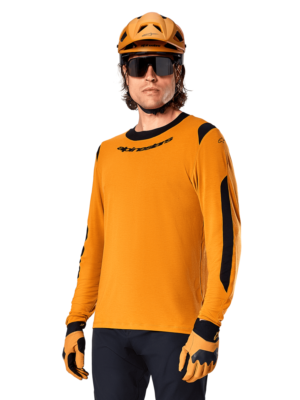 Alpinestars A-Dura Dri Wool Jersey z długim rękawem, koszulka rowerowa MTB, ciemnozłota i czarna, z odprowadzającej wilgoć mieszanki wełny merino i paneli siatkowych, rowerzysta w pasującym kasku, okularach przeciwsłonecznych i rękawicach