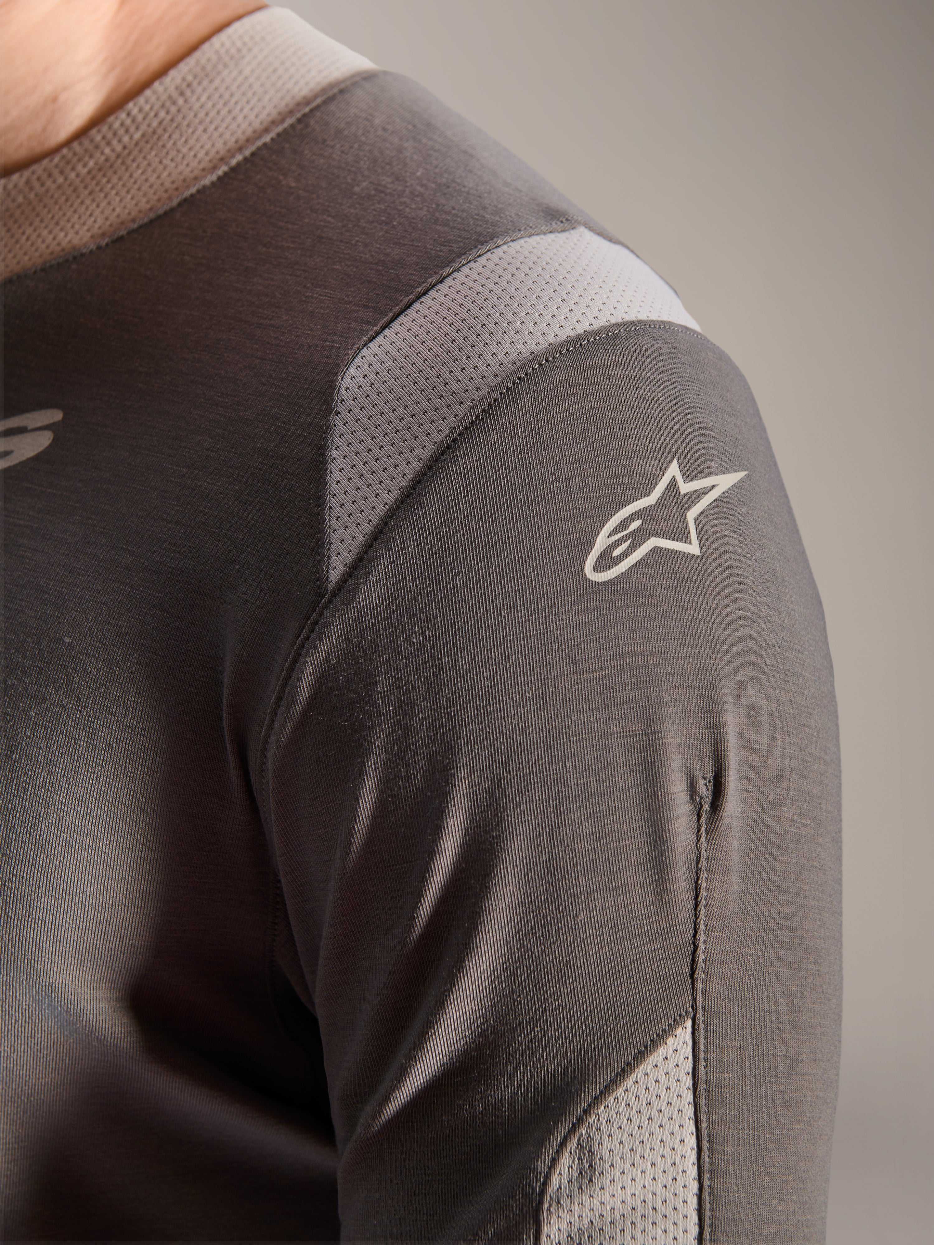 Alpinestars A-Dura Dri Wool Jersey - Long Sleeve, ciemnoszara, szczegółowy widok ramienia i rękawa z jasnoszarymi siateczkowymi panelami wentylacyjnymi i białym logo Astars na technicznej tkaninie drirelease.