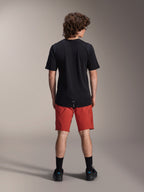 Model w spodenkach Alpinestars A-Dura Elite w kolorze Dark Orange i czarnej koszulce z krótkim rękawem A-Dura Dri Wool, widok od tyłu, w komplecie z czarnymi skarpetami i butami rowerowymi, profesjonalna odzież do kolarstwa górskiego