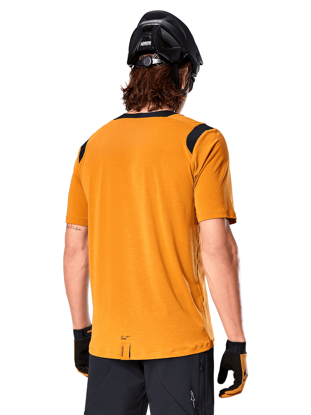 Alpinestars A-Dura Dri Wool Short Sleeve Jersey, Dark Gold, widok z tyłu mężczyzny ubranego w koszulkę z krótkim rękawem z czarnymi panelami z siatki na ramionach, w zestawieniu z czarnym kaskiem MTB i rękawicami, odzież na rower górski o regularnym kroju