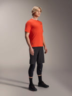 Koszulka Alpinestars A-Aria Astar z krótkim rękawem w kolorze Spicy Orange, prezentowana przez modela z czarnymi spodenkami MTB i ochraniaczami kolan, lekka oddychająca odzież na rower górski, intensywny pomarańczowy kolor z subtelnym czarnym logo