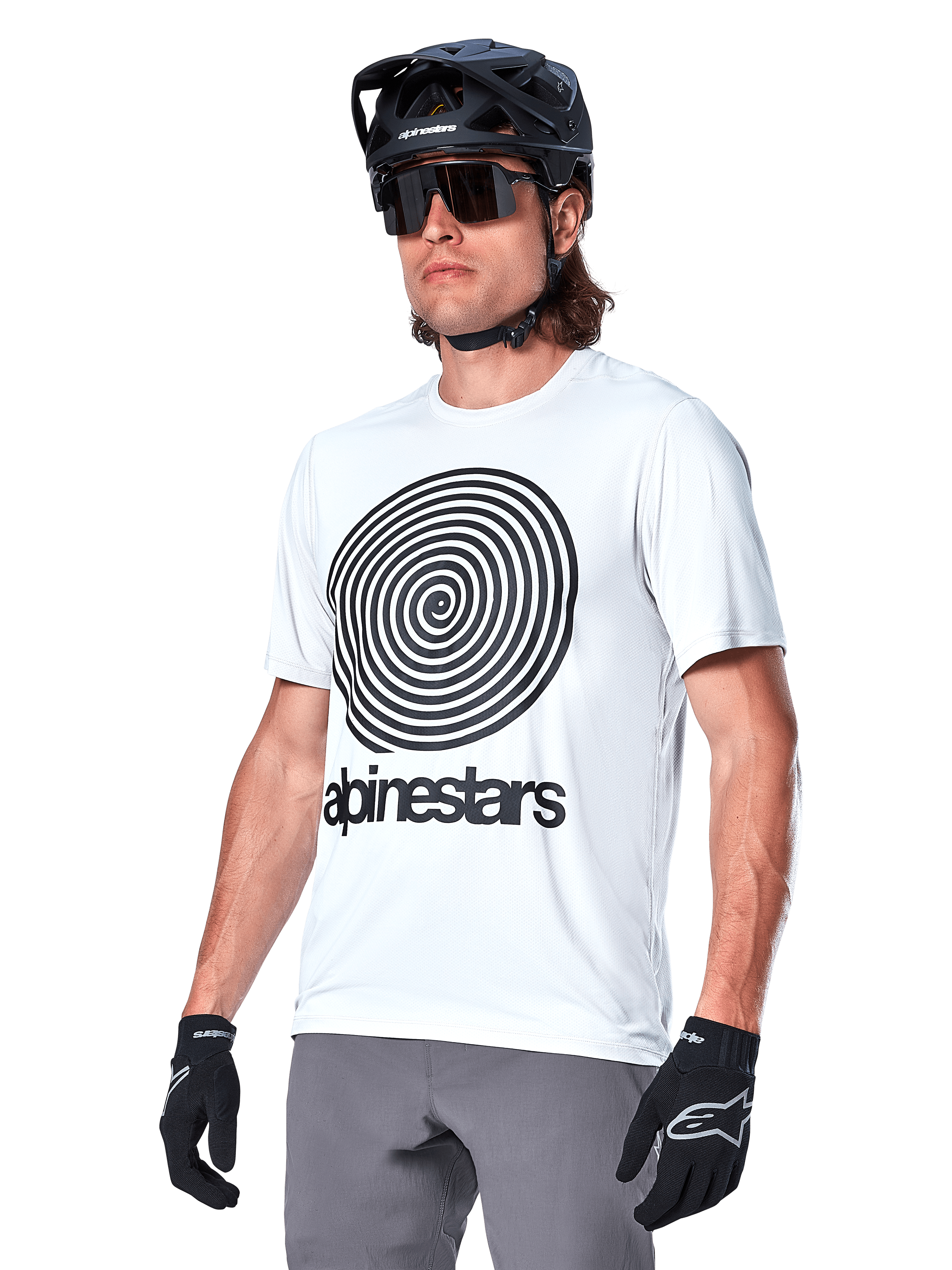 Koszulka Alpinestars A-Dura Oscar z krótkim rękawem, biała z czarną spiralną grafiką heritage i logo, noszona z czarnym kaskiem MTB i rękawiczkami, sportowa odzież do kolarstwa górskiego