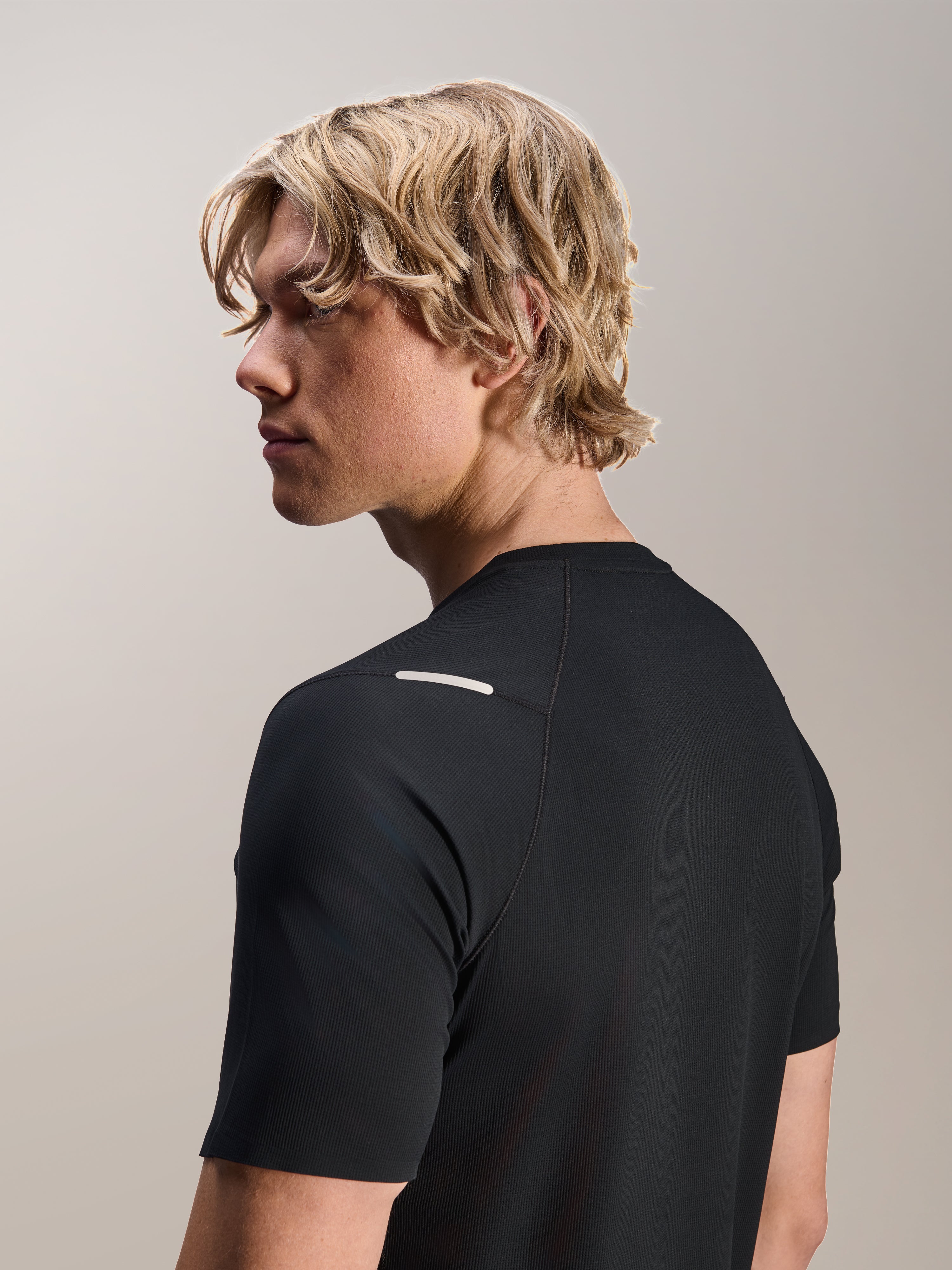 Mężczyzna w koszulce Alpinestars A-Aria Switch Jersey, krótki rękaw, czarna, widok z boku i z tyłu prezentujący sportowe dopasowanie i detale na ramieniu, lekka, oddychająca odzież rowerowa MTB