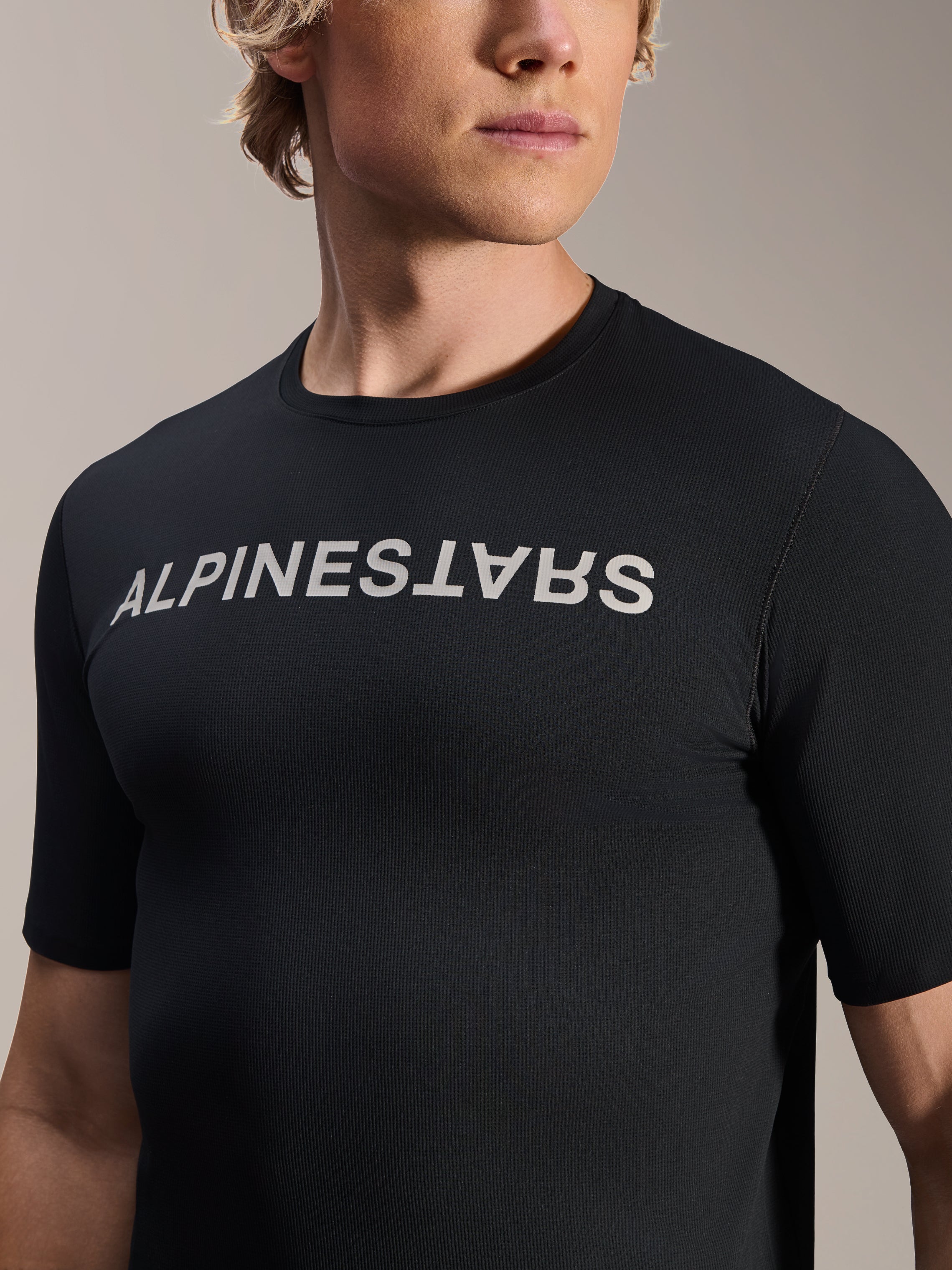 Koszulka Alpinestars A-Aria Switch z krótkim rękawem, czarna, z białym logo Alpinestars na klatce piersiowej, sportowy krój, oddychająca męska odzież rowerowa