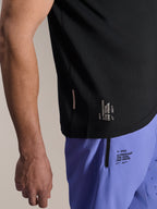 Alpinestars A-Aria Switch Short Sleeve Jersey, czarna koszulka MTB, zbliżenie na boczny dolny brzeg z białym brandingiem „ONE GOAL. ONE VISION.”, noszona z jasnofioletowymi szortami rowerowymi z pasującymi logo