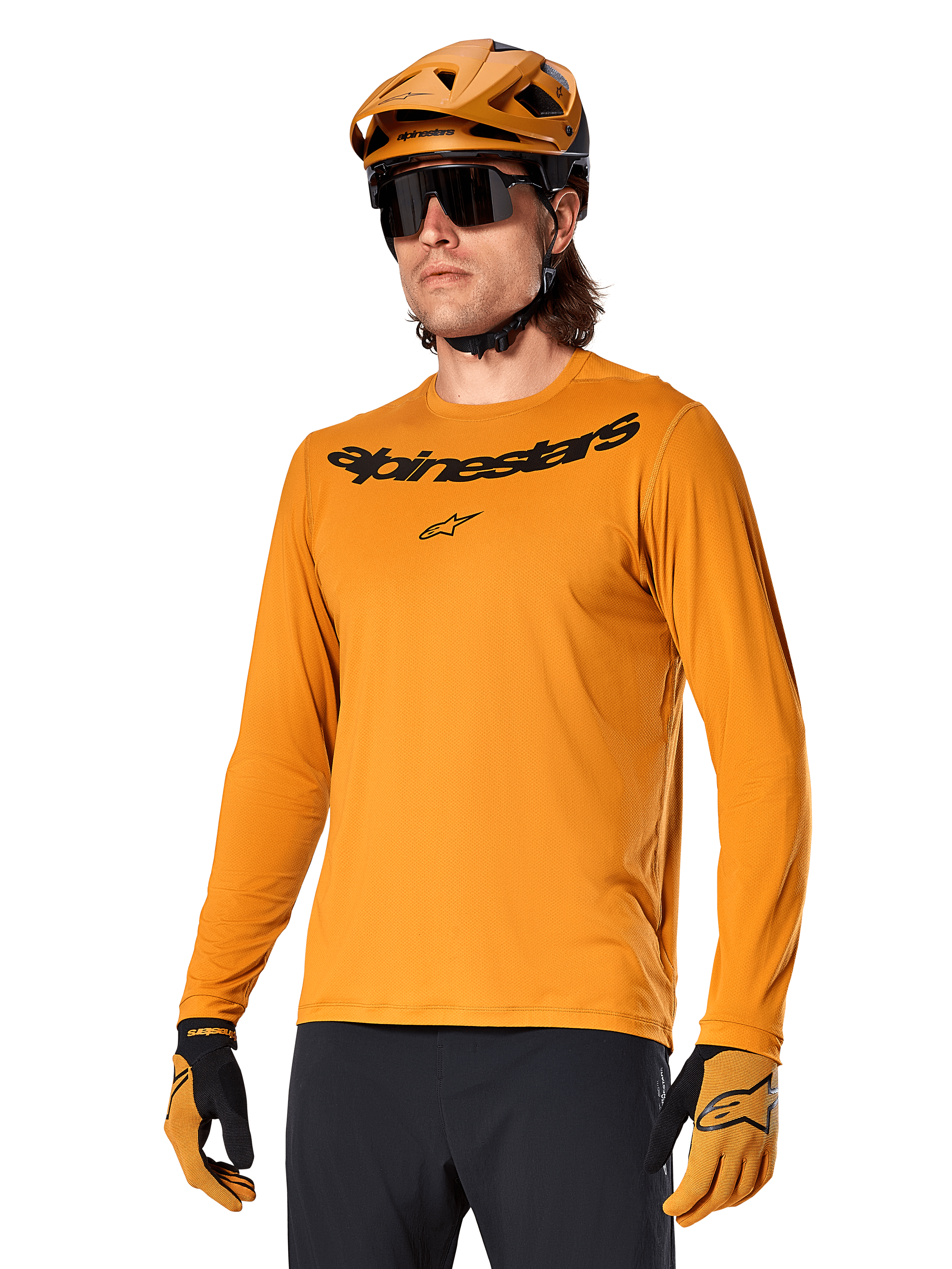 Alpinestars A-Dura Rocker Long Sleeve Jersey, koszulka rowerowa MTB, kolor ciemnozłoty, osoba w koszulce z dopasowanym kaskiem i rękawiczkami, sportowy spójny zestaw z napisem Alpinestars na piersi
