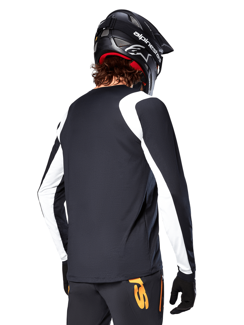 Rowerzysta MTB ubrany w koszulkę Alpinestars A-Supra Oscar z długim rękawem, czarna z białymi panelami na ramionach i rękawach, widok z tyłu, czarny kask i rękawice, spodnie z pomarańczowymi akcentami, wytrzymała odzież rowerowa off-road