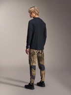 Alpinestars A-Dura Camo Pant, MTB Pants, Brown Camouflage, worn with a black long-sleeve jersey and black sneakers, rear view showing tapered legs and elasticated cuffs, performance apparel for off-road cycling