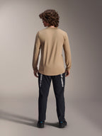 Alpinestars A-Dura Astar Long Sleeve Jersey, jasnobrązowa, widok z tyłu prezentujący przedłużony tył, noszona z czarnymi spodniami z brandingiem Alpinestars, odzież rowerowa MTB