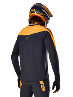 Alpinestars A-Supra Race Jersey - Long Sleeve, czarno-pomarańczowa, widok z tyłu na rowerzystę w pasującym kasku i spodniach MTB, sportowy krój z mikroperforowaną teksturą, profesjonalny strój wyścigowy MTB